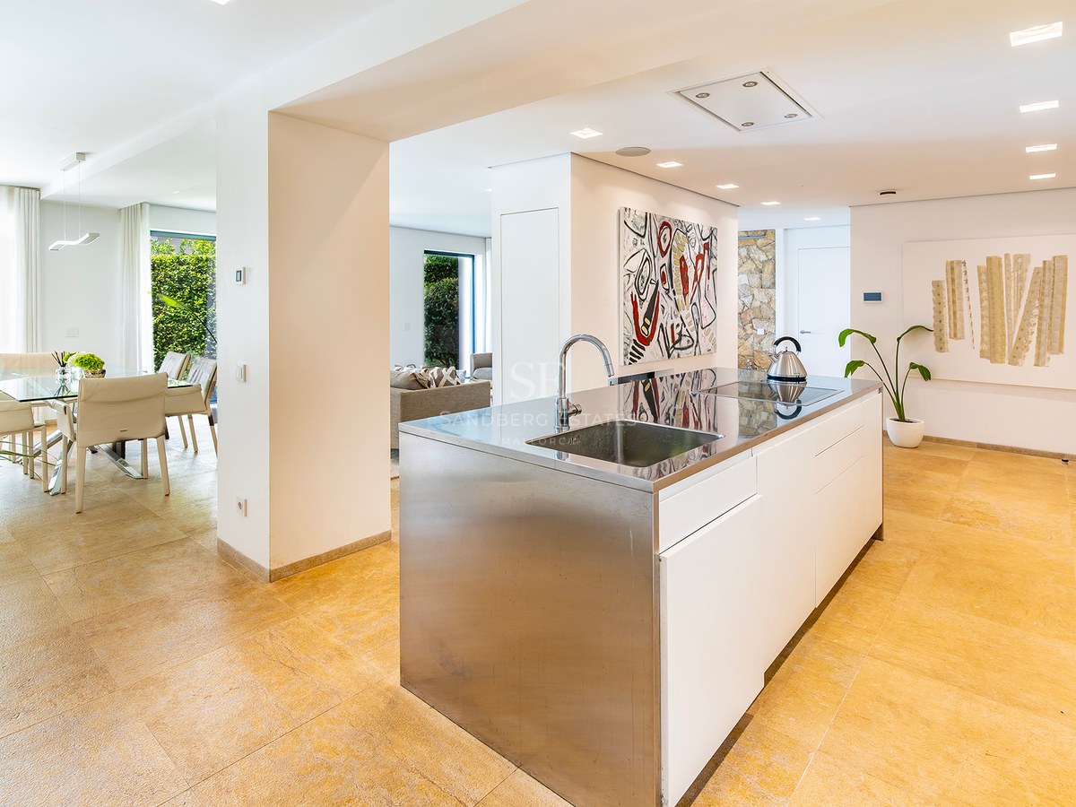 Cuisine contemporaine avec îlot en acier inoxydable, sol en pierre naturelle et salle à manger lumineuse attenante.