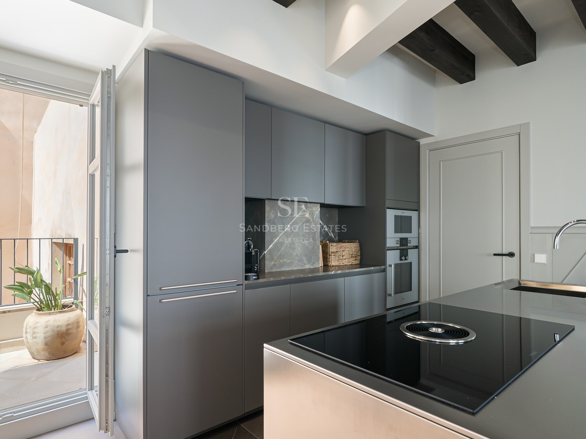 Contemporary charcoal grey kitchen featuring an island with induction hob, marble splashback, and balcony access.