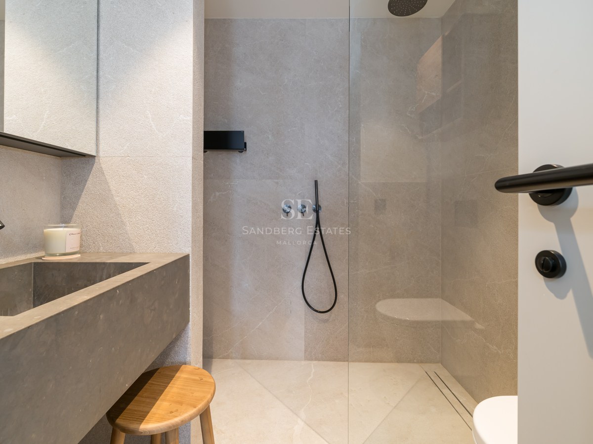 Contemporary bathroom featuring a grey stone washbasin, black matte faucets, and a glass-enclosed walk-in shower.