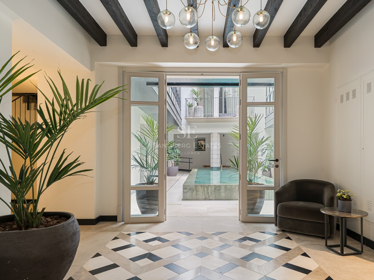 Luxury entrance hall with geometric floor tiles leading to a sunlit internal courtyard and plunge pool.