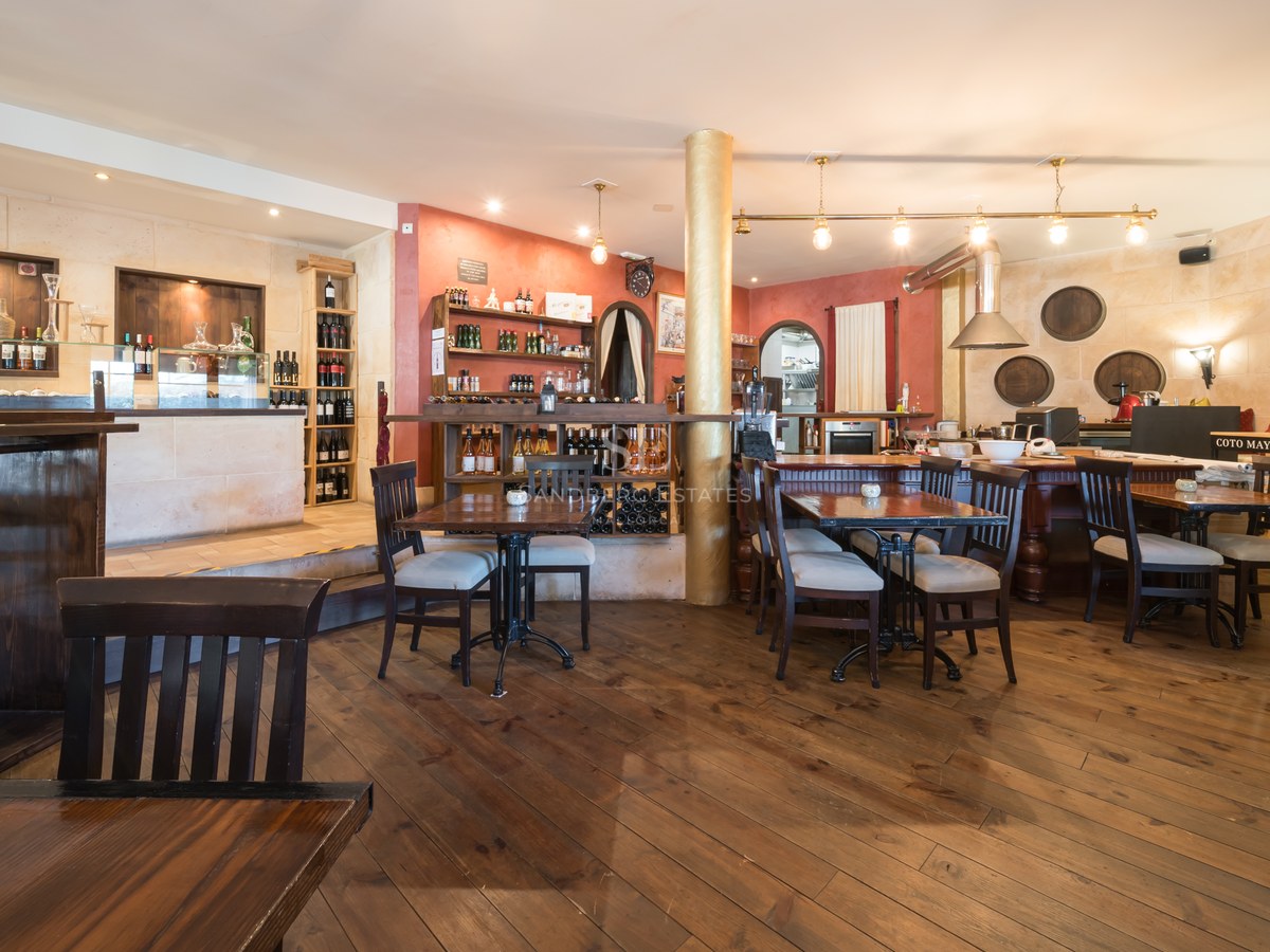 Amplia bodega de estilo rústico con suelos de madera oscura, paredes de piedra natural y zona de bar integrada.