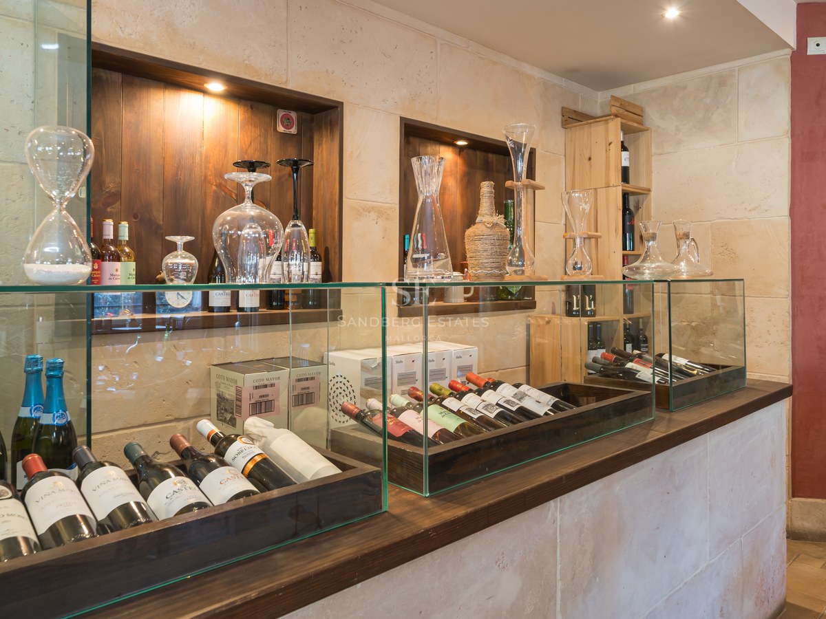 Interior de una bodega de lujo con vitrinas de cristal, paredes de piedra natural y estanterías de madera oscura.