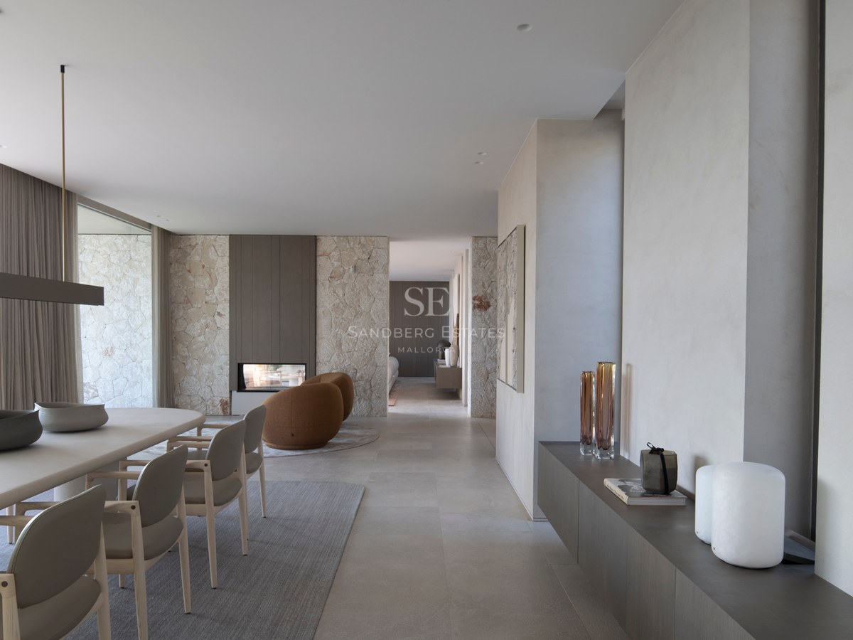 Salle à manger contemporaine avec mur en pierre naturelle, cheminée moderne et sol en grès cérame grand format.