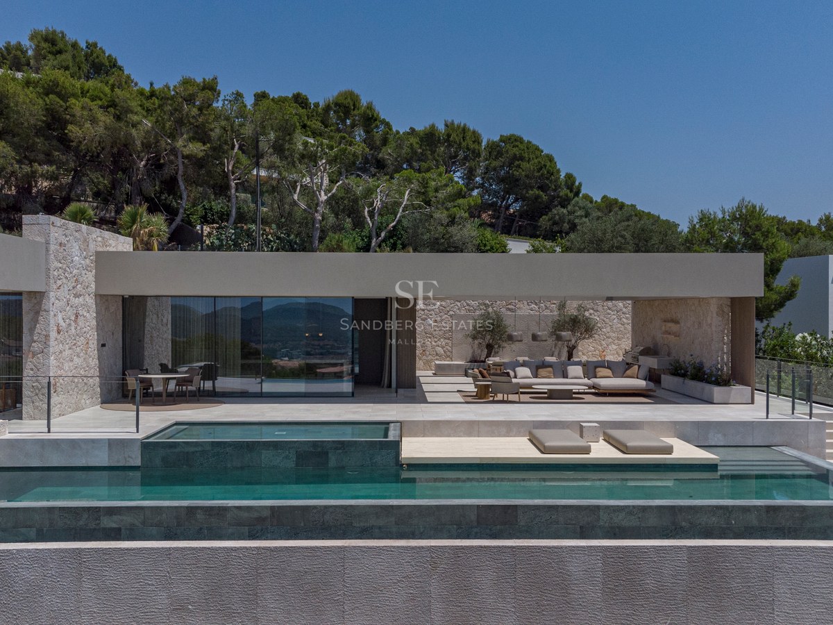 Extérieur d'une villa contemporaine avec piscine à plusieurs niveaux, terrasse couverte et murs en pierre naturelle.