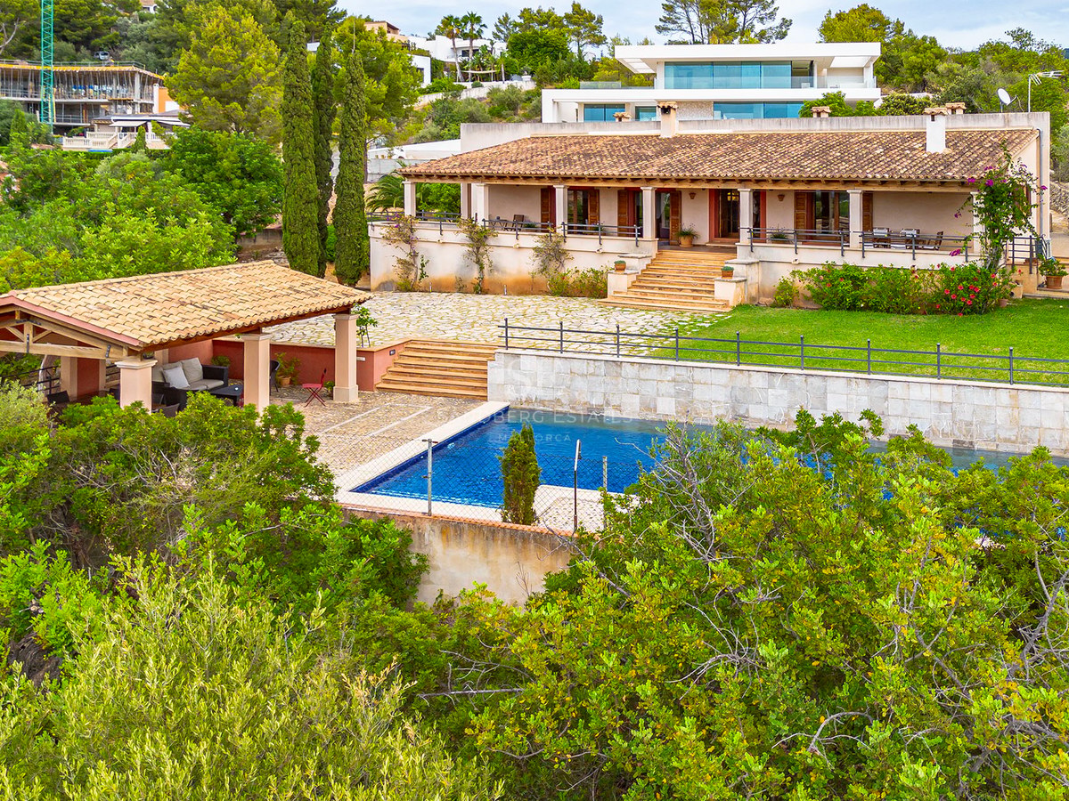 Vue extérieure d'une villa méditerranéenne avec toit en terre cuite, piscine et jardins en terrasses.