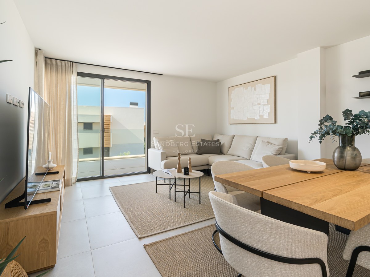 Contemporary living and dining room featuring a cream sofa, oak furniture, and floor-to-ceiling glass doors to a terrace.