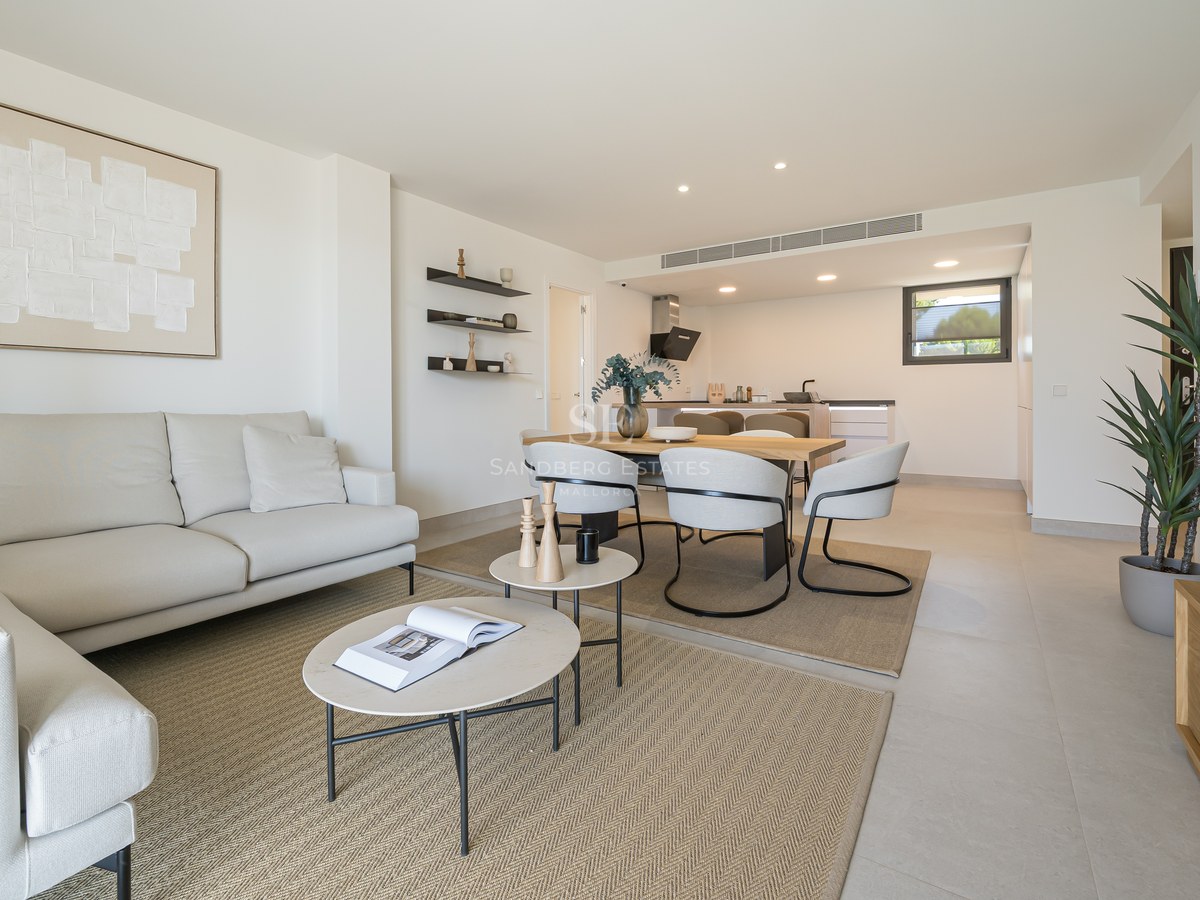 Bright open-plan living room with cream sofa, round coffee tables, and dining area in neutral tones.