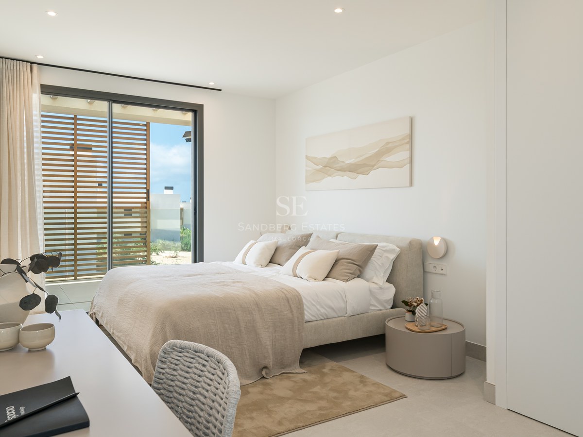 Bright contemporary bedroom with a double bed, white wardrobes, and sliding glass doors opening to a sunlit terrace.