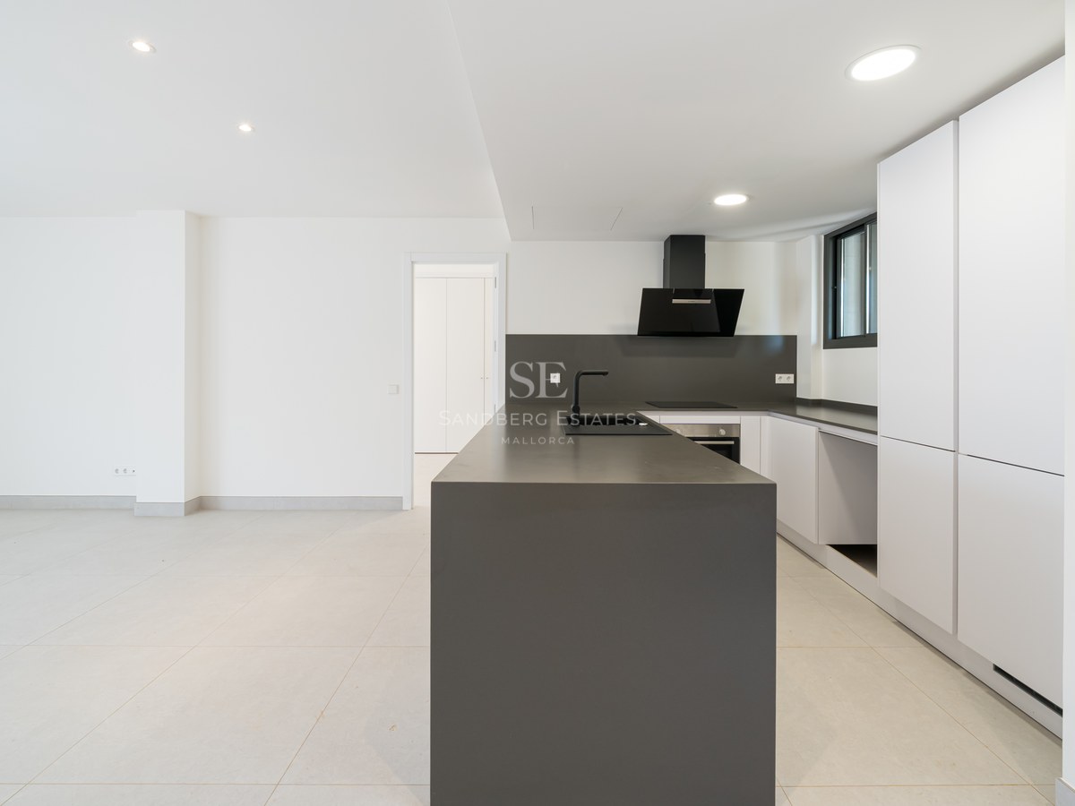 Contemporary kitchen featuring a dark grey central island, white cabinetry, and matte black fixtures in a bright space.