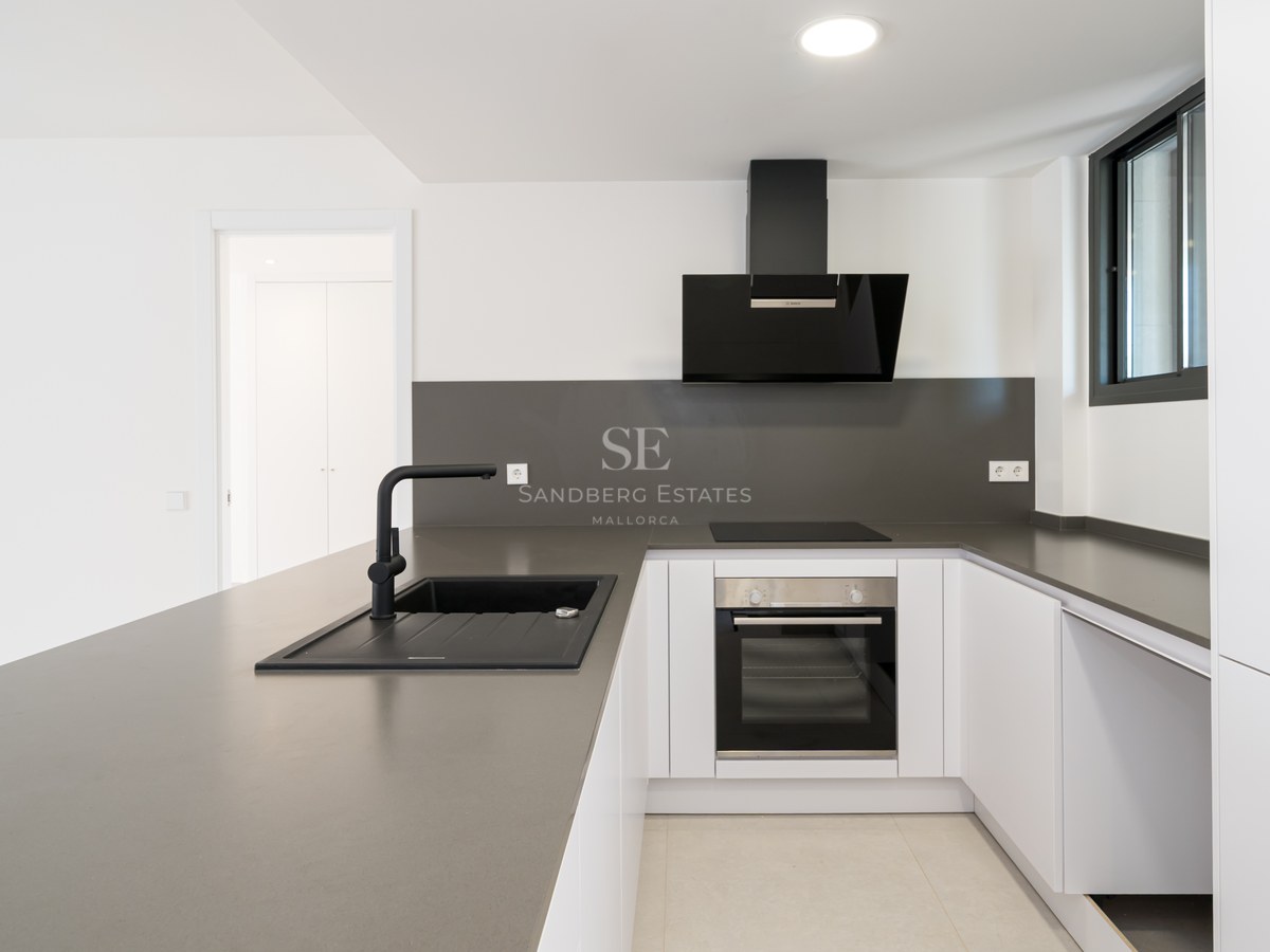 Clean white kitchen featuring grey quartz countertops, a black sink, and integrated Bosch appliances.