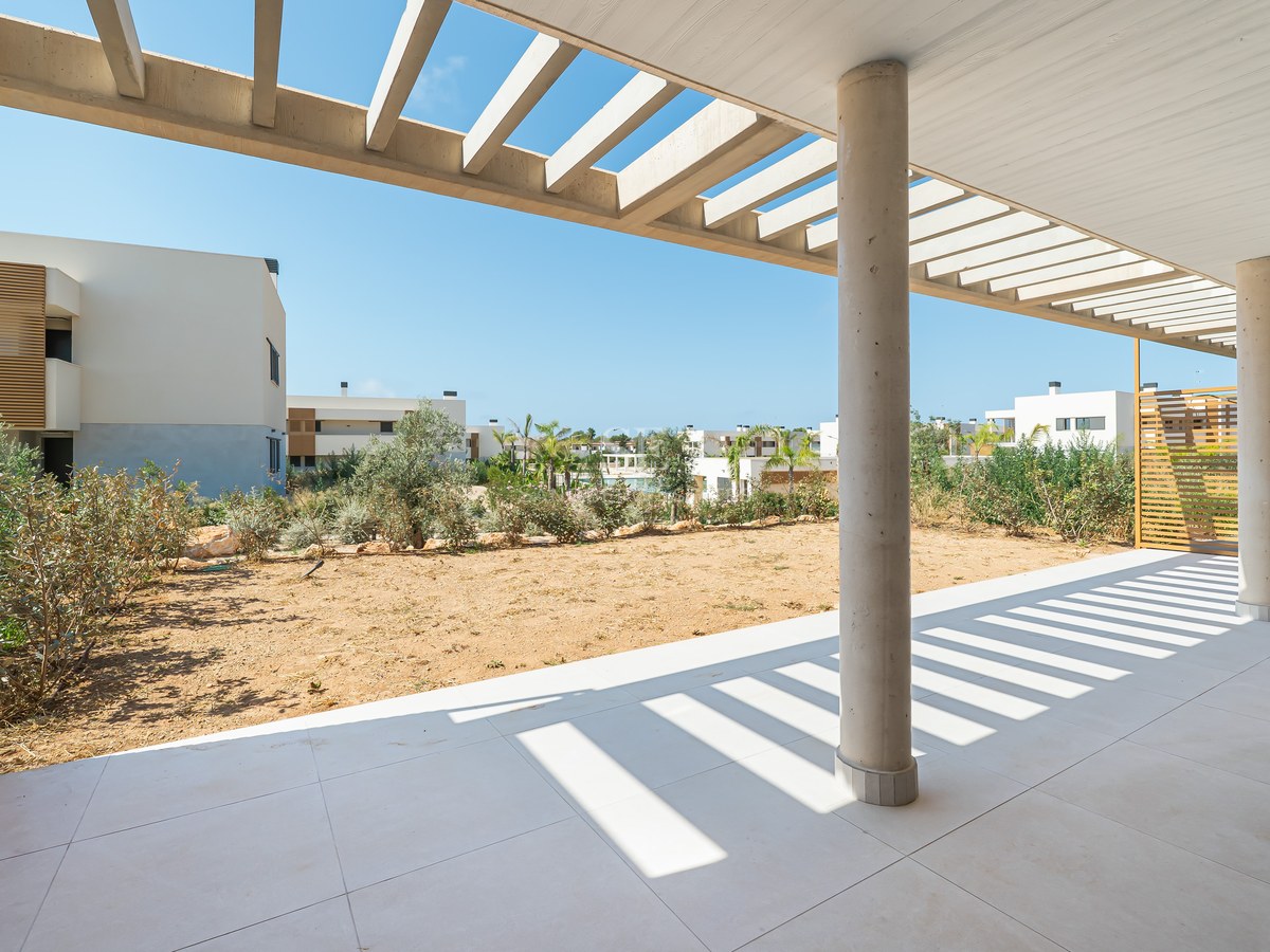 Expansive covered terrace featuring light porcelain tiles, concrete columns, and a wooden pergola under bright sunlight.