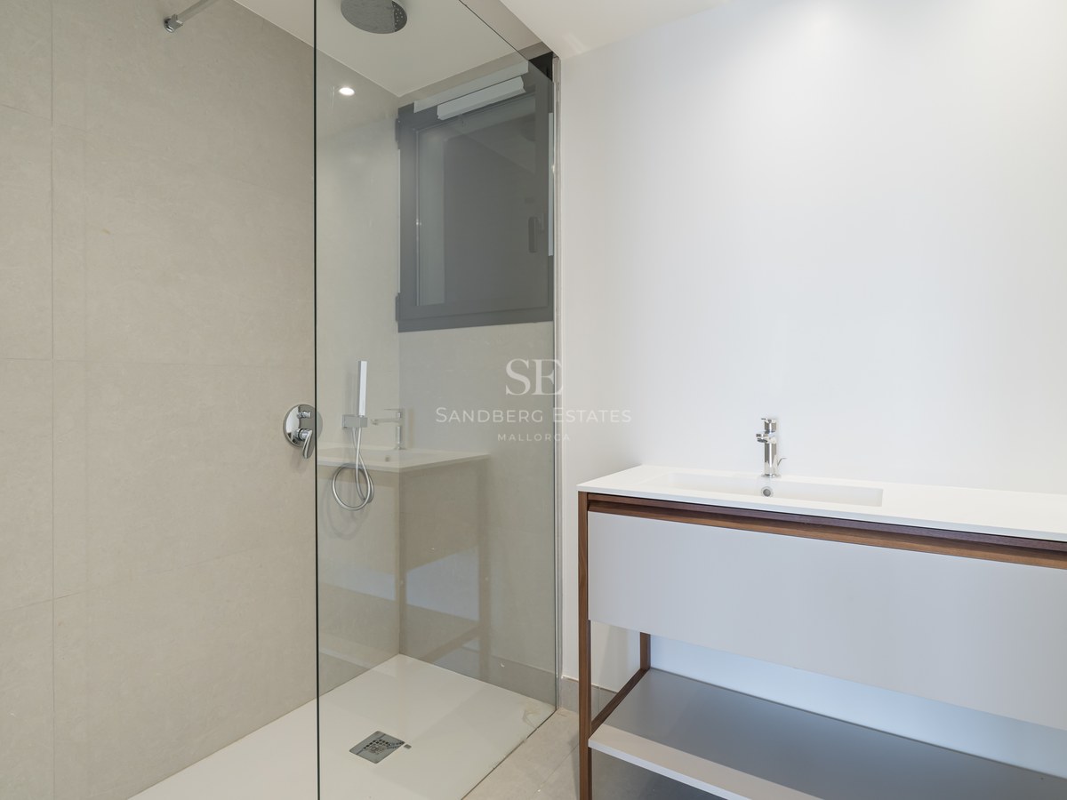 Modern bathroom featuring a glass-enclosed walk-in shower with beige tiles and a sleek white and wood vanity.