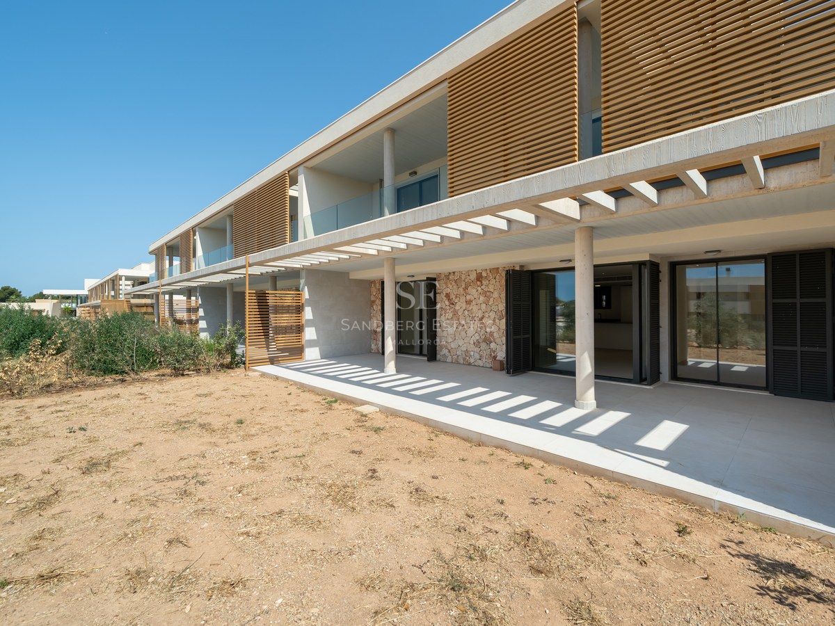 Modern residential facade featuring natural stone masonry, wooden slats, and a wide porcelain tile terrace.