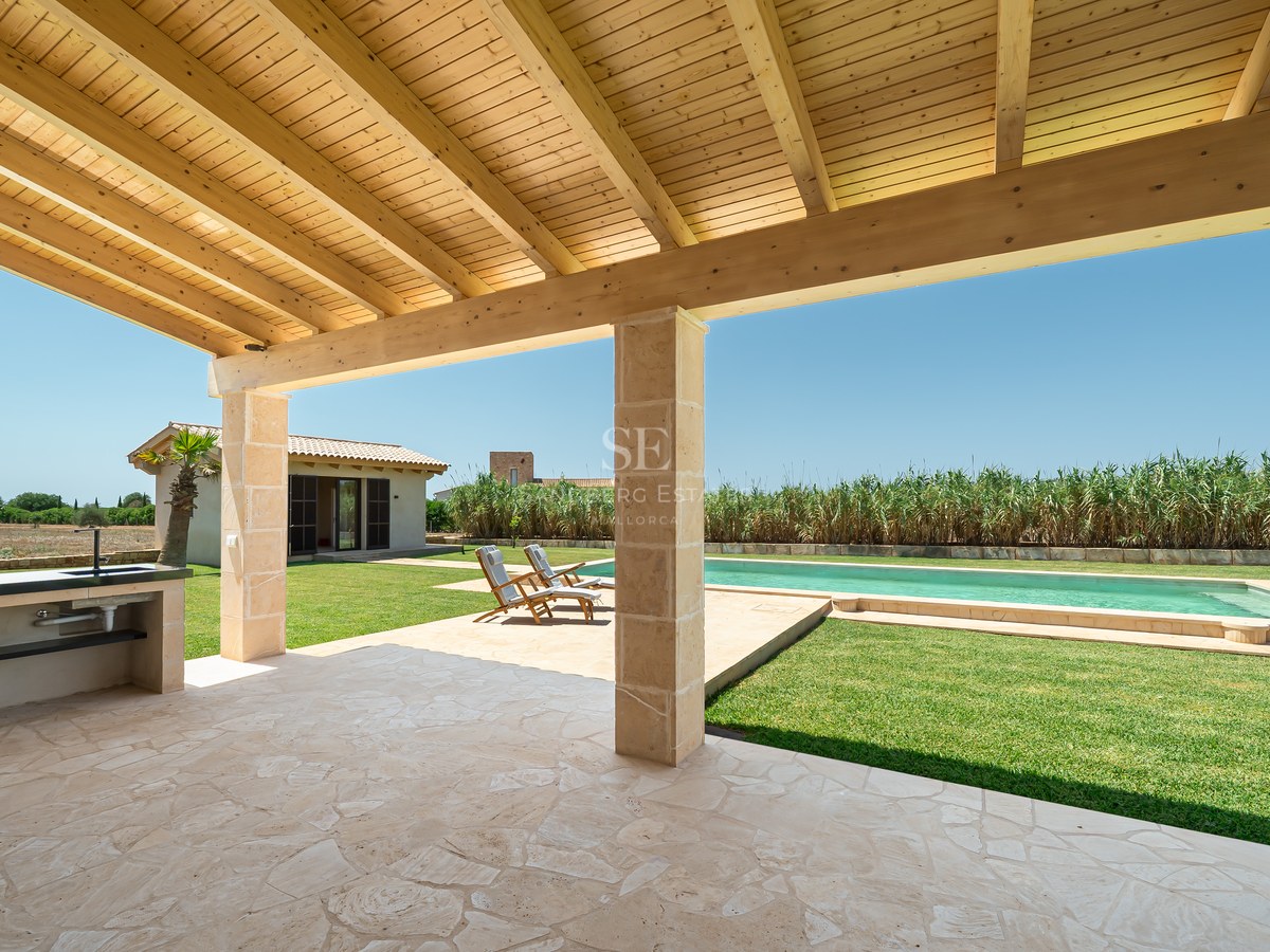 Terrasse couverte avec plafond en bois, évier extérieur et vue sur la piscine et le jardin.