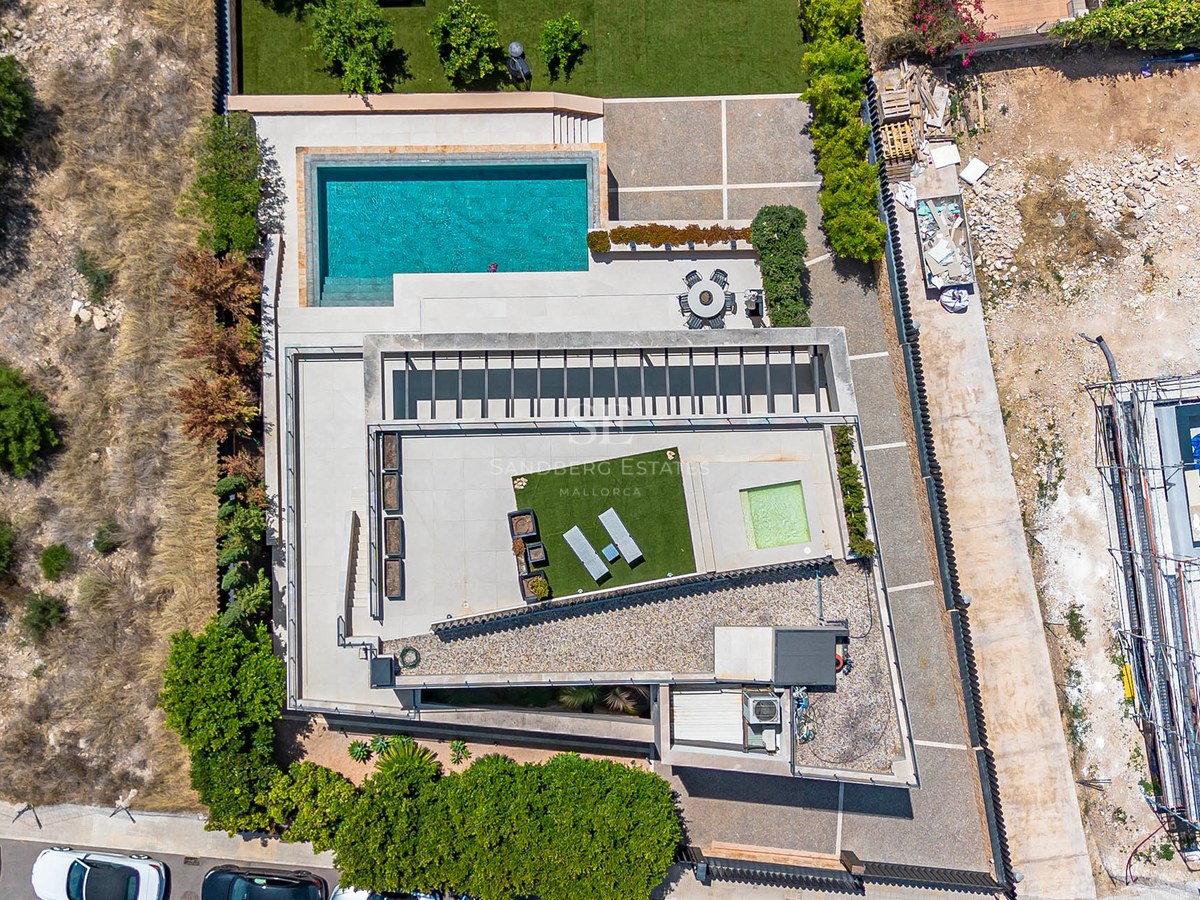Top-down aerial view of a modern villa featuring a rectangular pool, multiple tiled terraces, and manicured lawns.