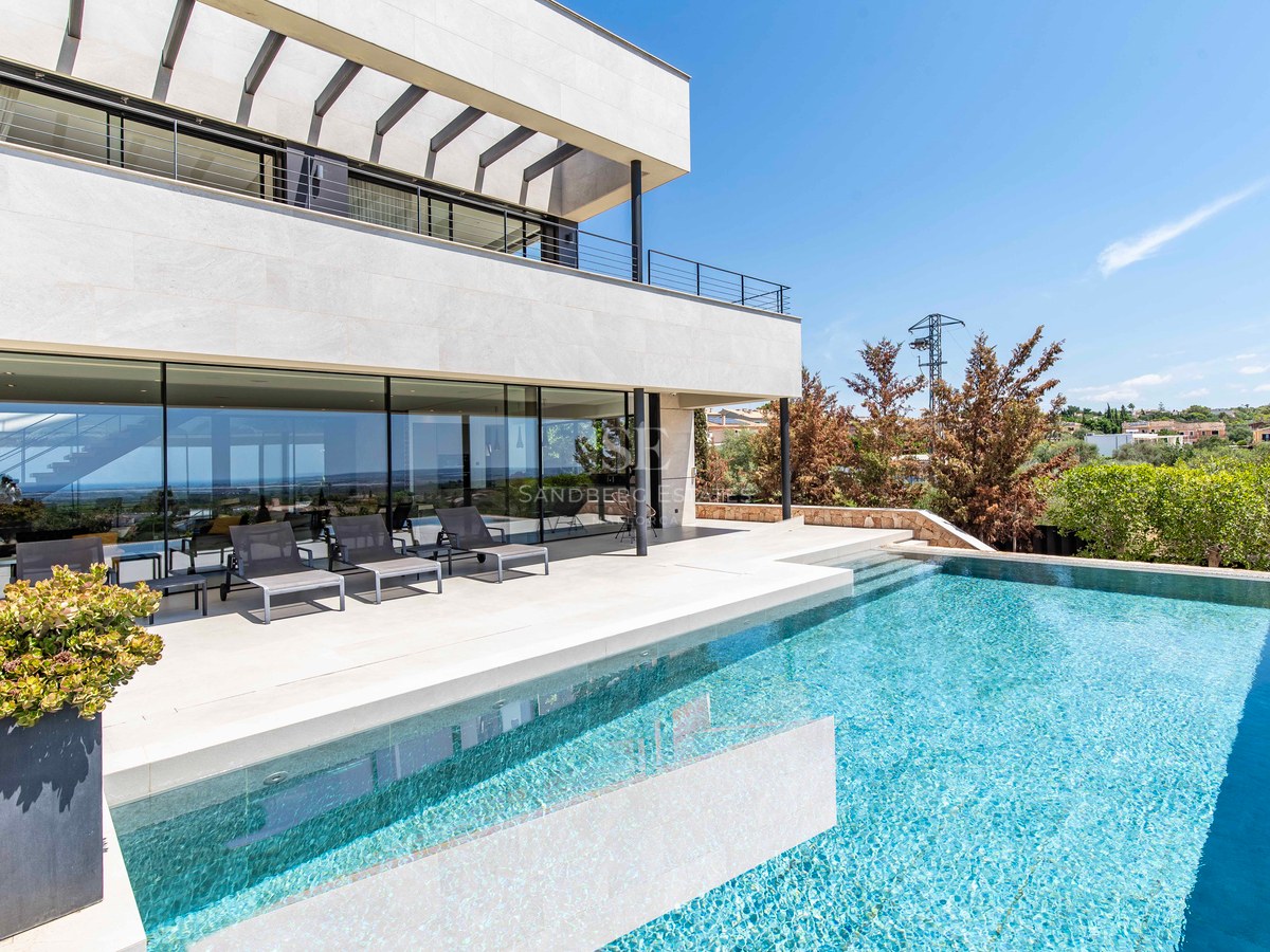 Modern luxury villa featuring an infinity pool, natural stone terrace, and floor-to-ceiling glass walls.
