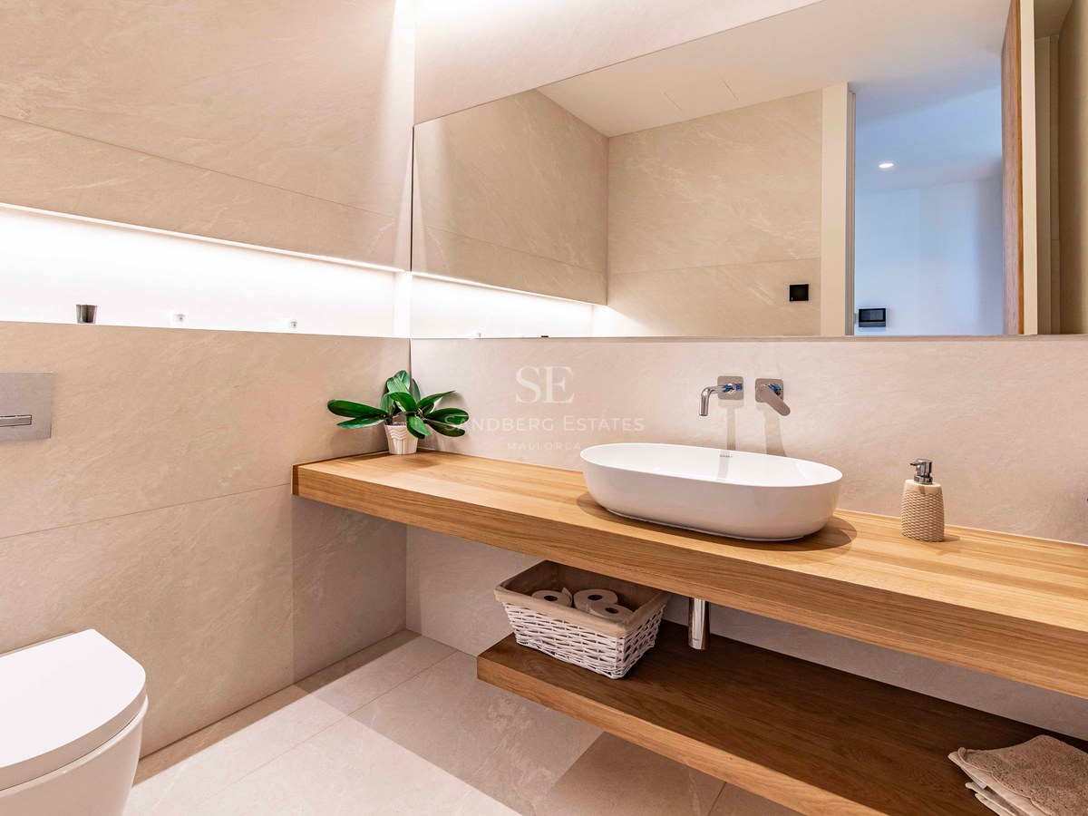 Modern bathroom featuring a floating oak vanity, white vessel sink, large mirror, and warm recessed LED lighting.