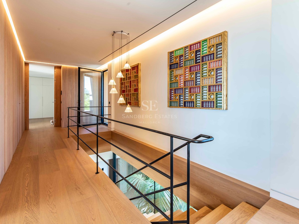 Modern hallway featuring oak flooring, black metal railings, and vibrant geometric wall art in a bright space.