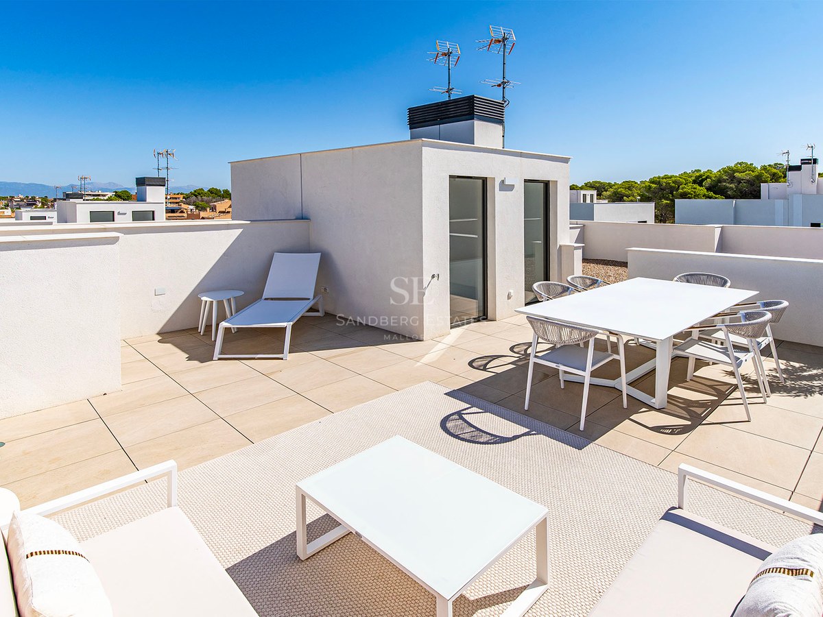 Terraza moderna soleada con muebles blancos, zona de comedor, área de descanso y suelos en tonos neutros.
