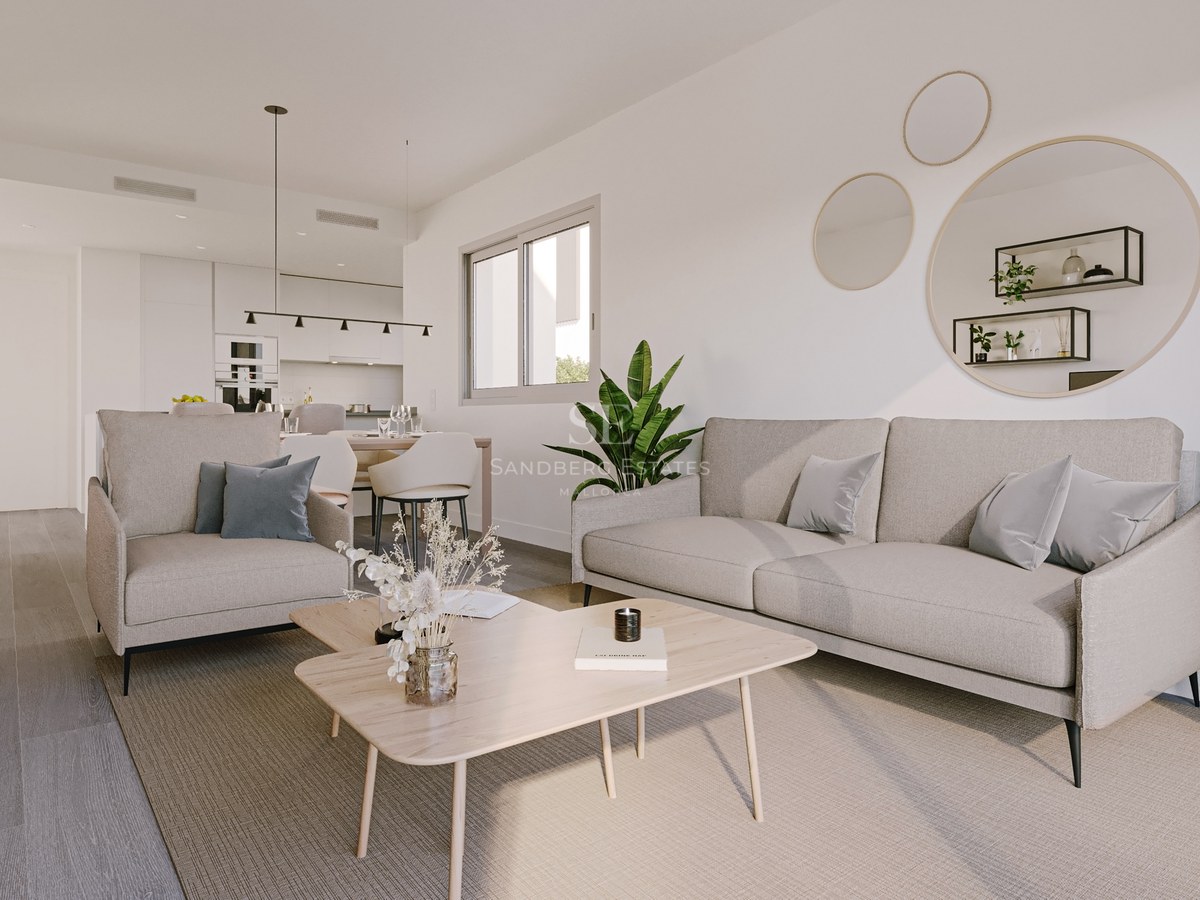 Modern living room with beige sofa, light wood coffee table, and open-plan kitchen in the background.
