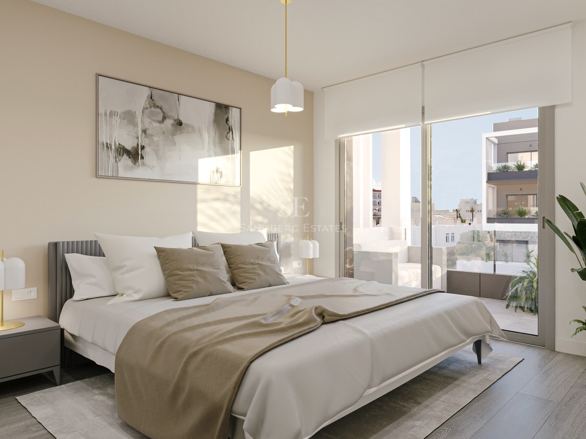 Contemporary bedroom with floor-to-ceiling glass doors opening to a balcony, featuring neutral tones and designer lighting.