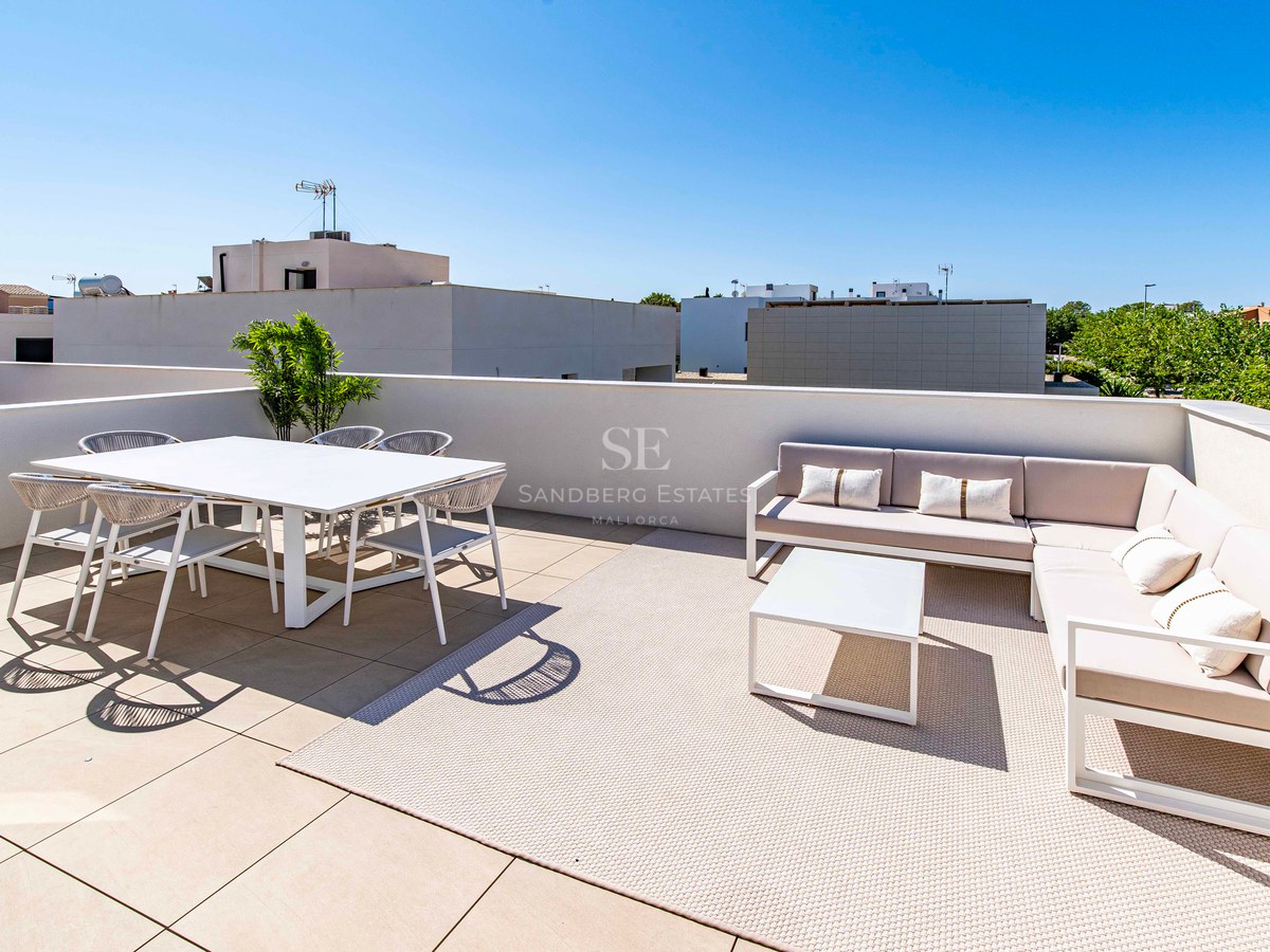 Sonnige Dachterrasse mit weißer Essgruppe und beigem Ecksofa unter strahlend blauem Himmel.