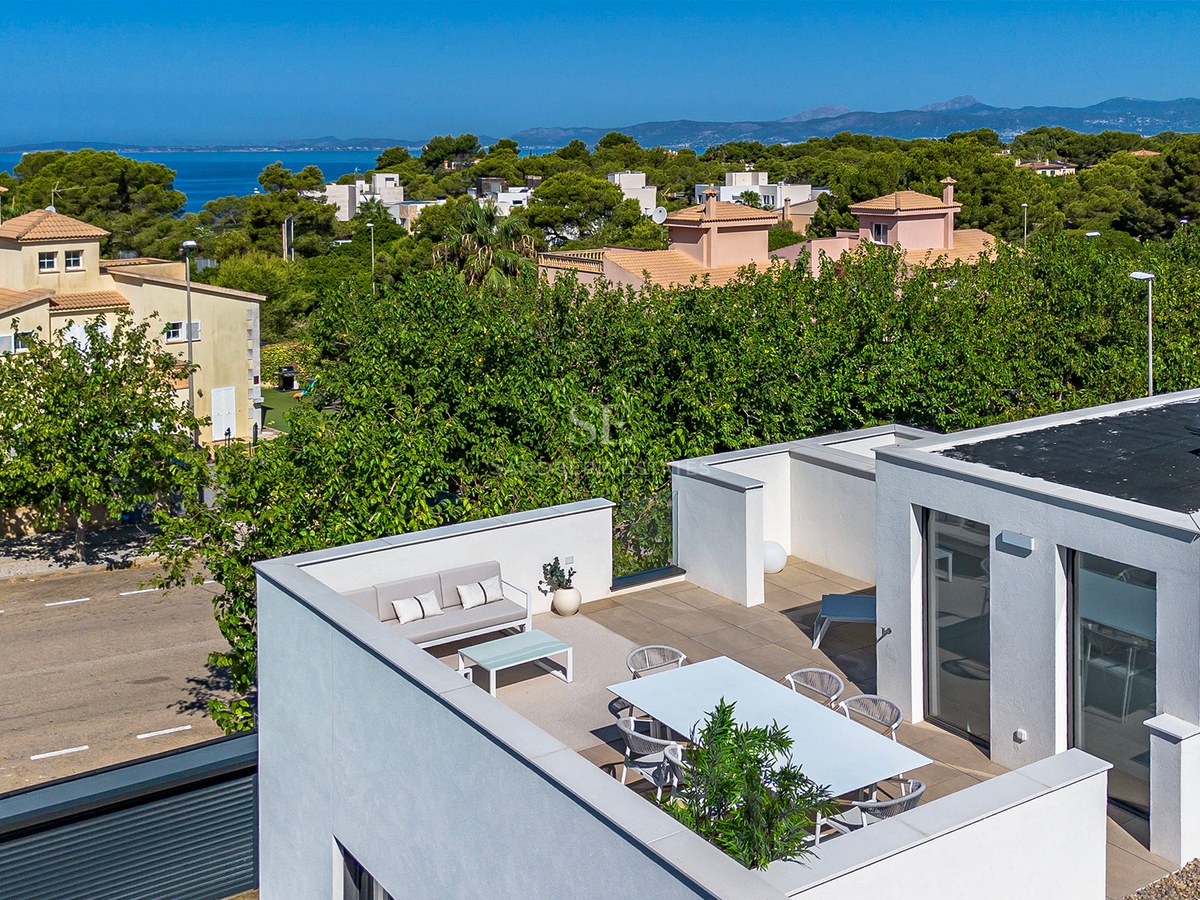 Moderne weiße Dachterrasse mit Essbereich und Loungemöbeln mit Blick auf das Mittelmeer und Pinienbäume.