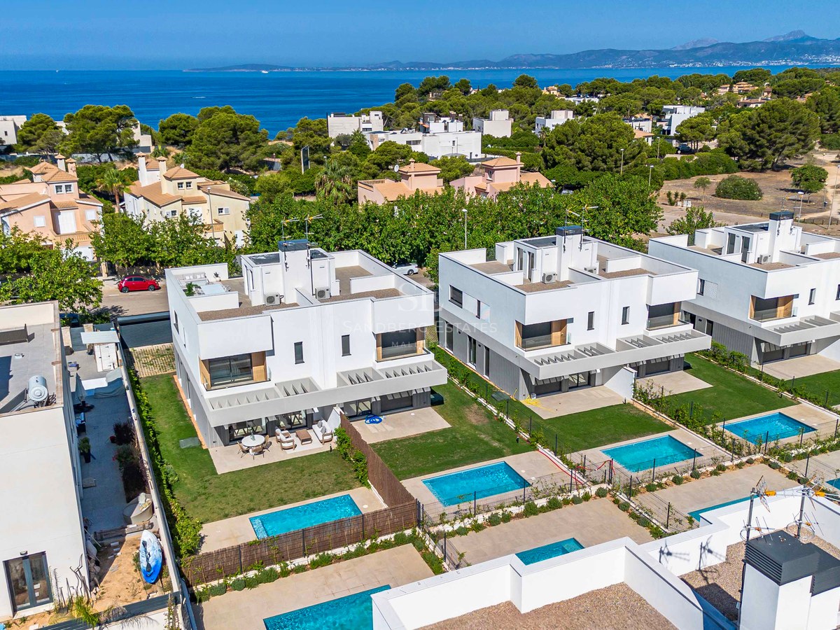 Luftaufnahme von weißen, modernen Villen mit privaten Pools und Blick auf das Mittelmeer und die Berge.