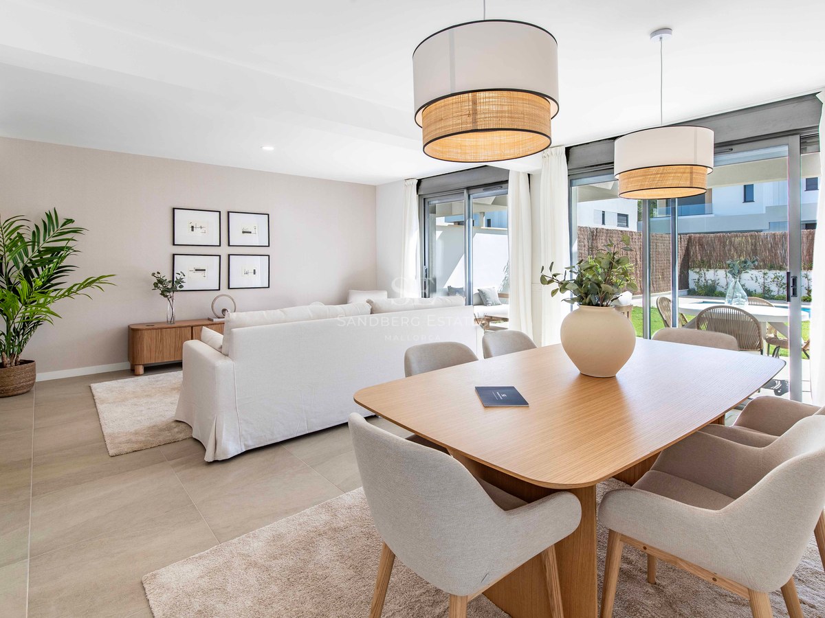 Modernes Wohnzimmer mit Eichentisch, hellem Sofa und raumhohen Glasfronten zum Garten und Pool.