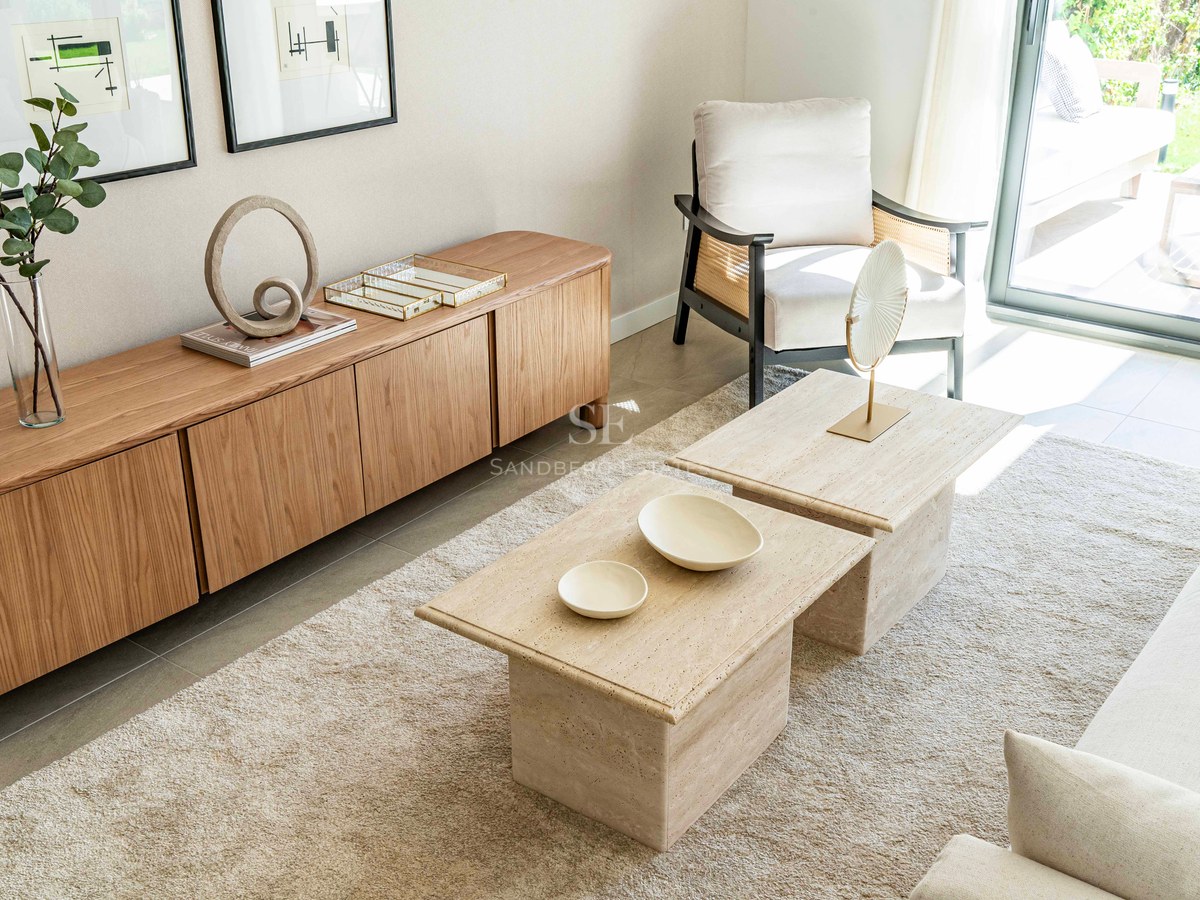 Helles Wohnzimmer mit Travertin-Couchtischen, einem Sideboard aus Eichenholz und direktem Zugang zur Terrasse.