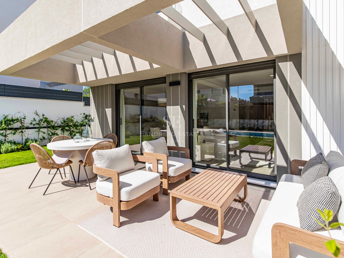 Terrasse mit Holzmöbeln und Essbereich neben einem privaten Garten unter einer modernen Pergola.