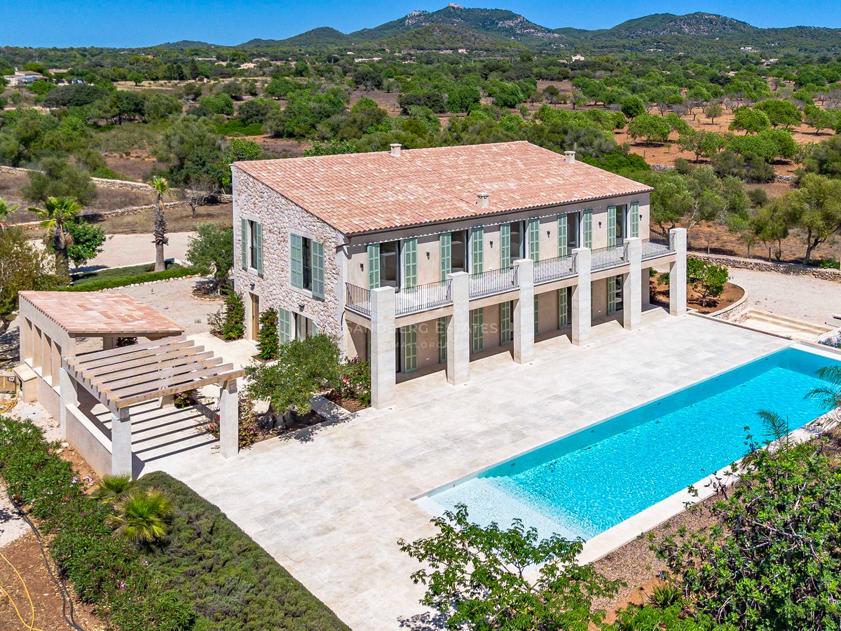 Vista aérea de una villa de piedra con piscina rectangular, persianas verdes y terraza de piedra natural.