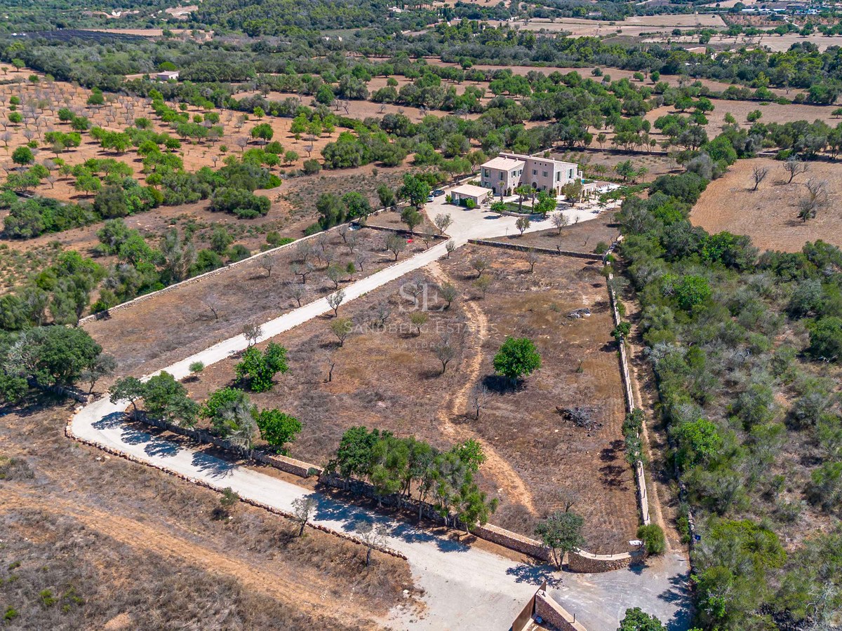 Vista aérea de una gran finca de piedra en una amplia parcela rodeada de muros de piedra seca y vegetación mediterránea.