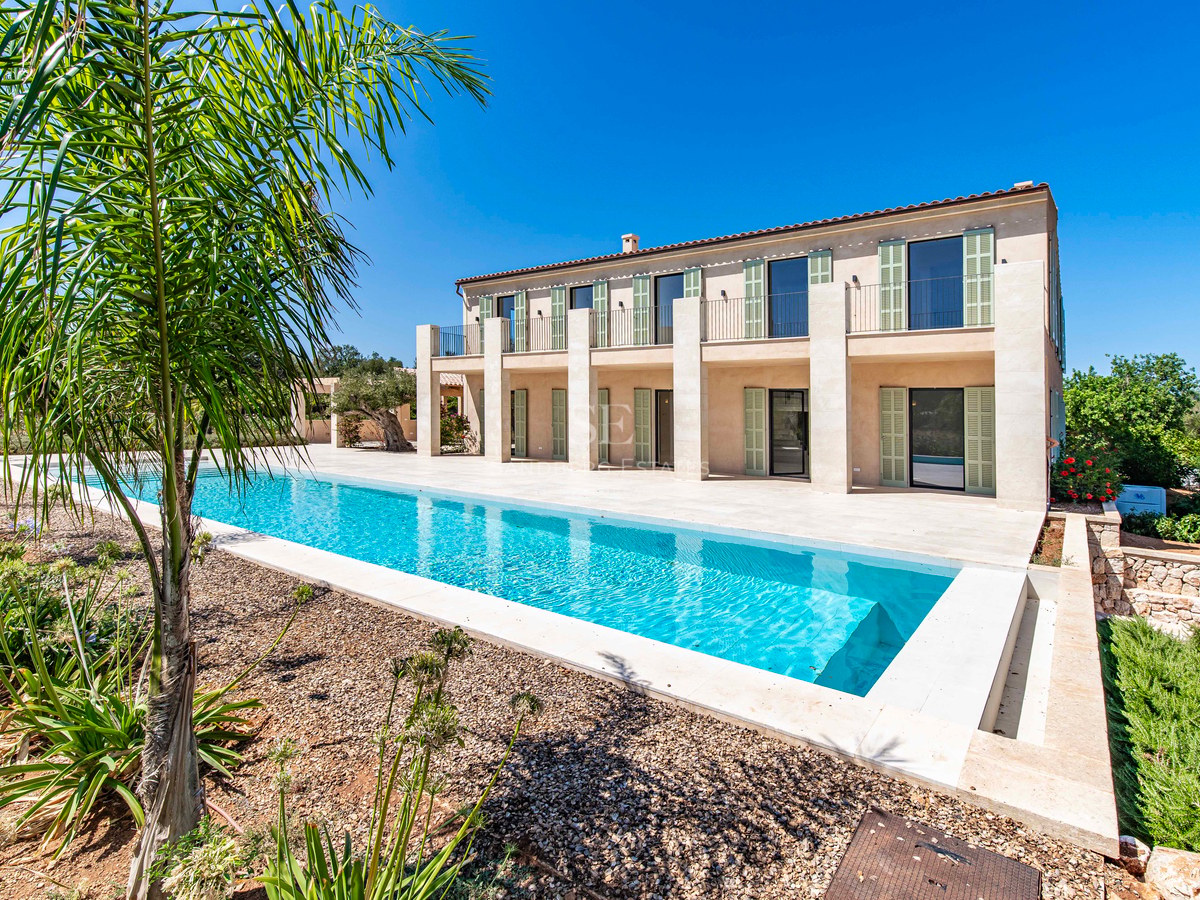 Villa moderna de dos plantas con fachada de piedra natural, persianas verdes y una piscina alargada turquesa.