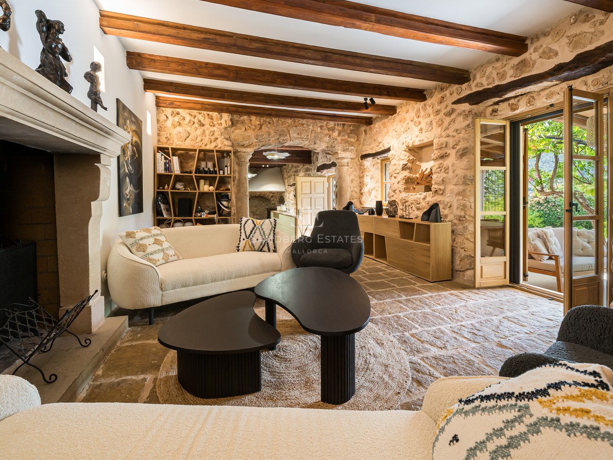 Luxury living room interior featuring exposed stone walls, timber beams, a statement fireplace, and terrace access.