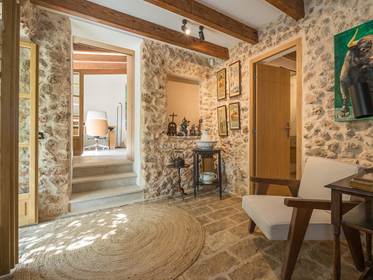 Entrance hallway featuring exposed natural stone walls, original timber ceiling beams, stone flooring, and a jute rug.