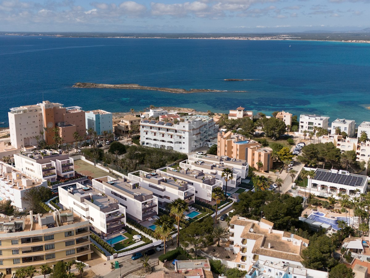 Aerial drone view of white modern apartment complexes and private pools overlooking a deep blue Mediterranean sea.