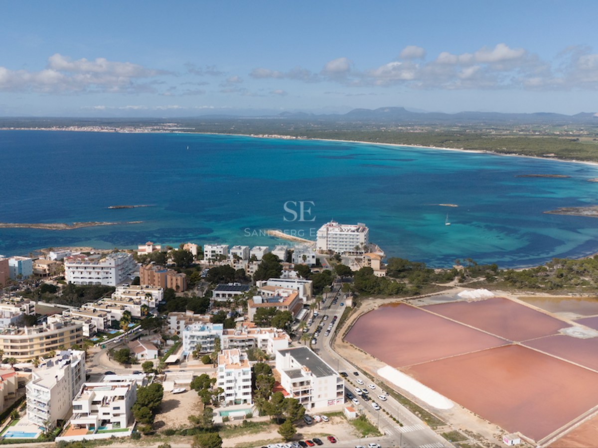 Drone view of turquoise Mediterranean sea, white seaside architecture, and vibrant pink salt evaporation ponds.