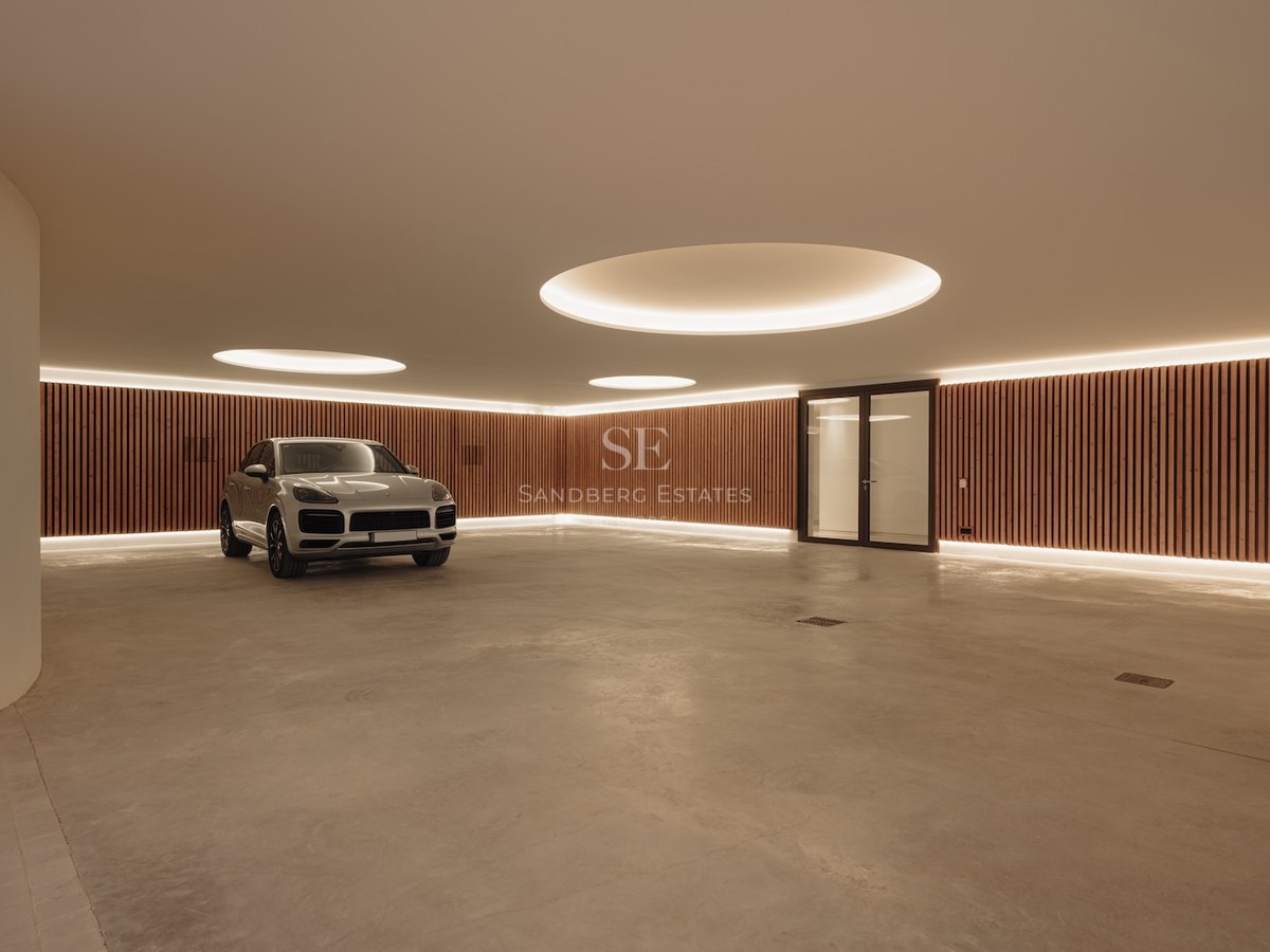 Garaje subterráneo moderno con suelos de hormigón pulido, paredes de madera y luces circulares empotradas.