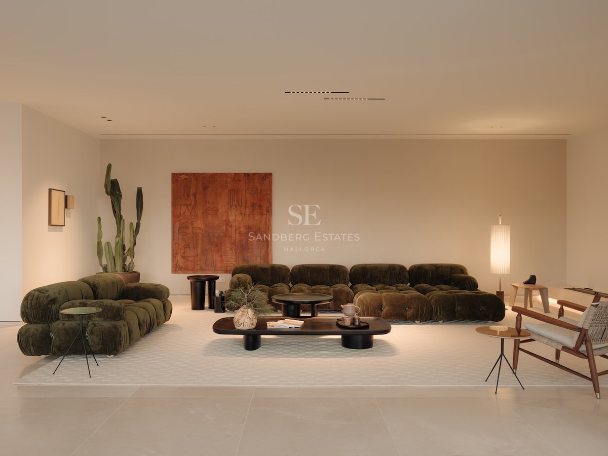 Salón moderno con sofás modulares verde oliva, un gran cuadro terracota y decoración minimalista sobre suelo claro.