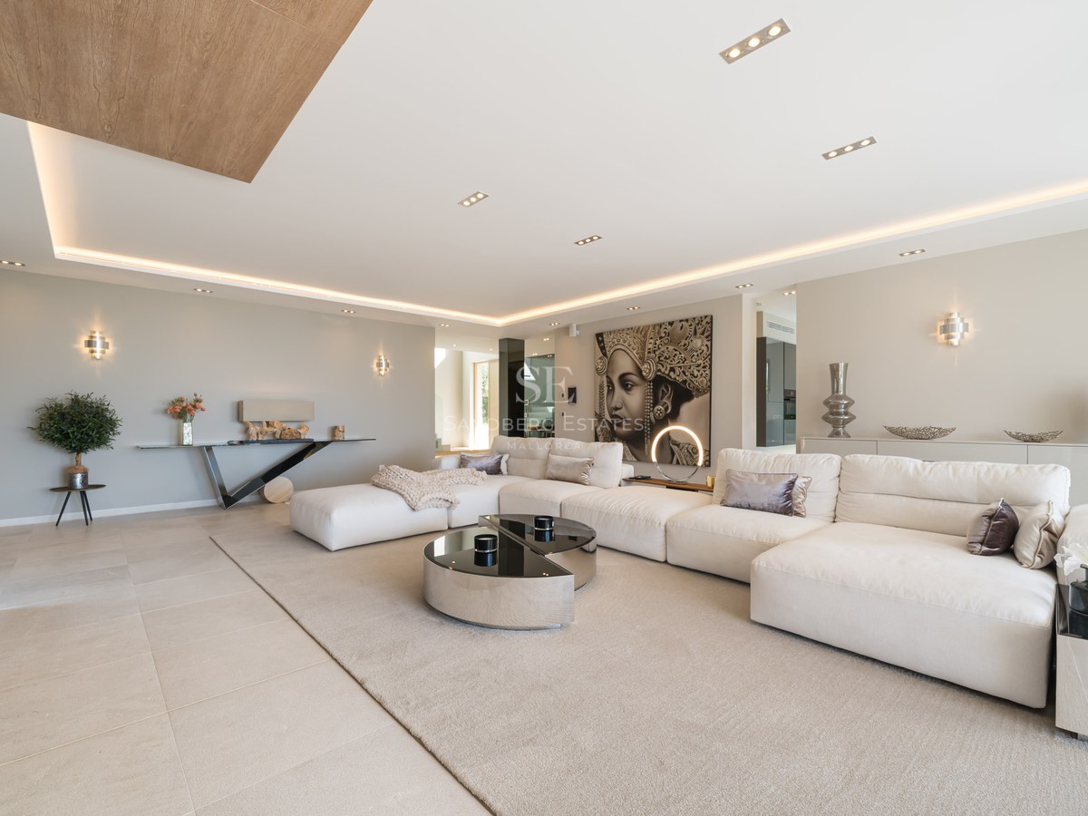 Large white modular sofa in a modern open-plan living room with porcelain flooring and warm LED lighting.