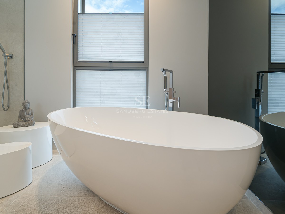 Minimalist bathroom featuring a white freestanding oval bathtub, natural stone flooring, and a walk-in shower.
