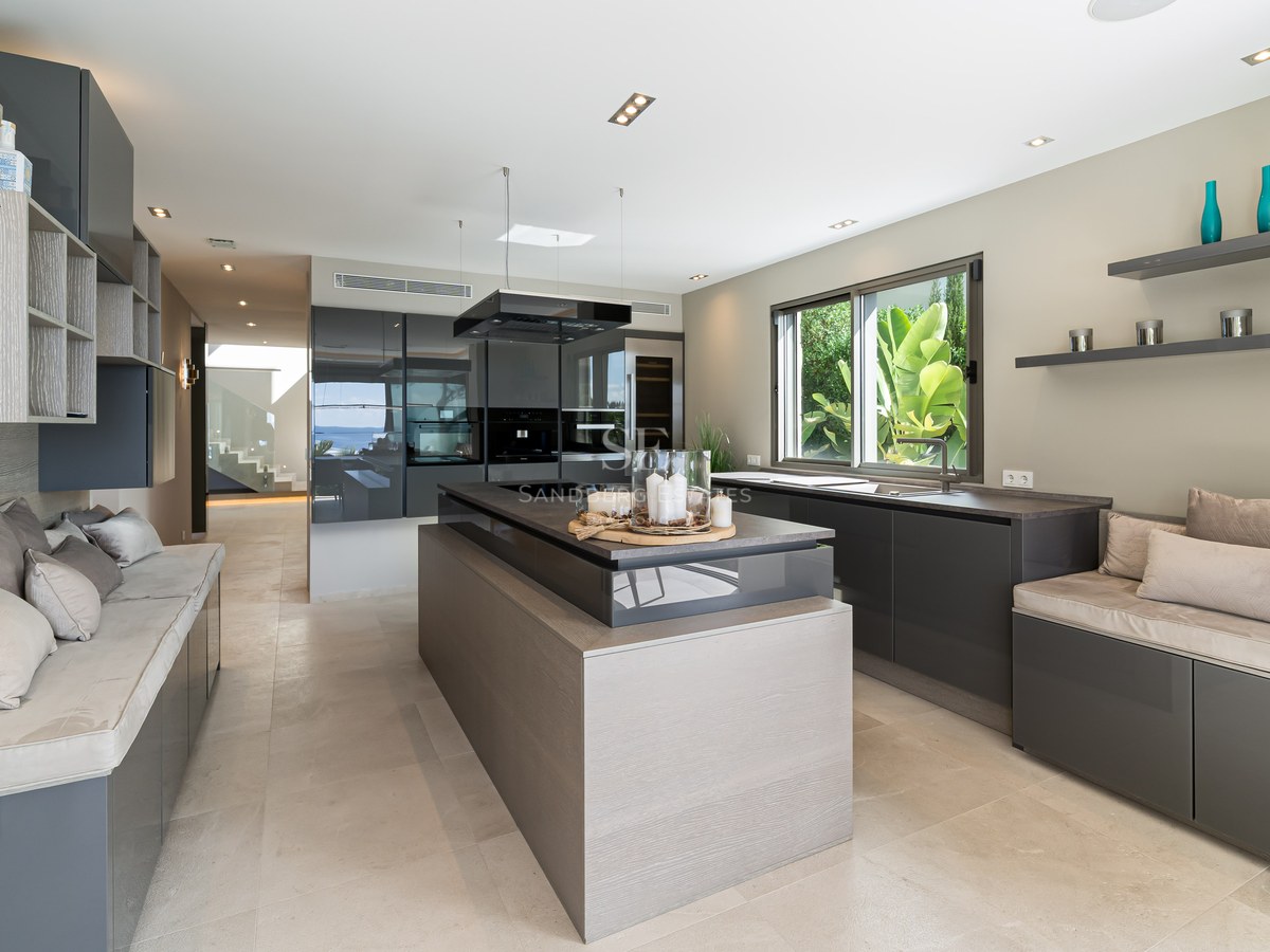 Modern kitchen featuring anthracite cabinetry, wood-textured island, and integrated lounge seating.