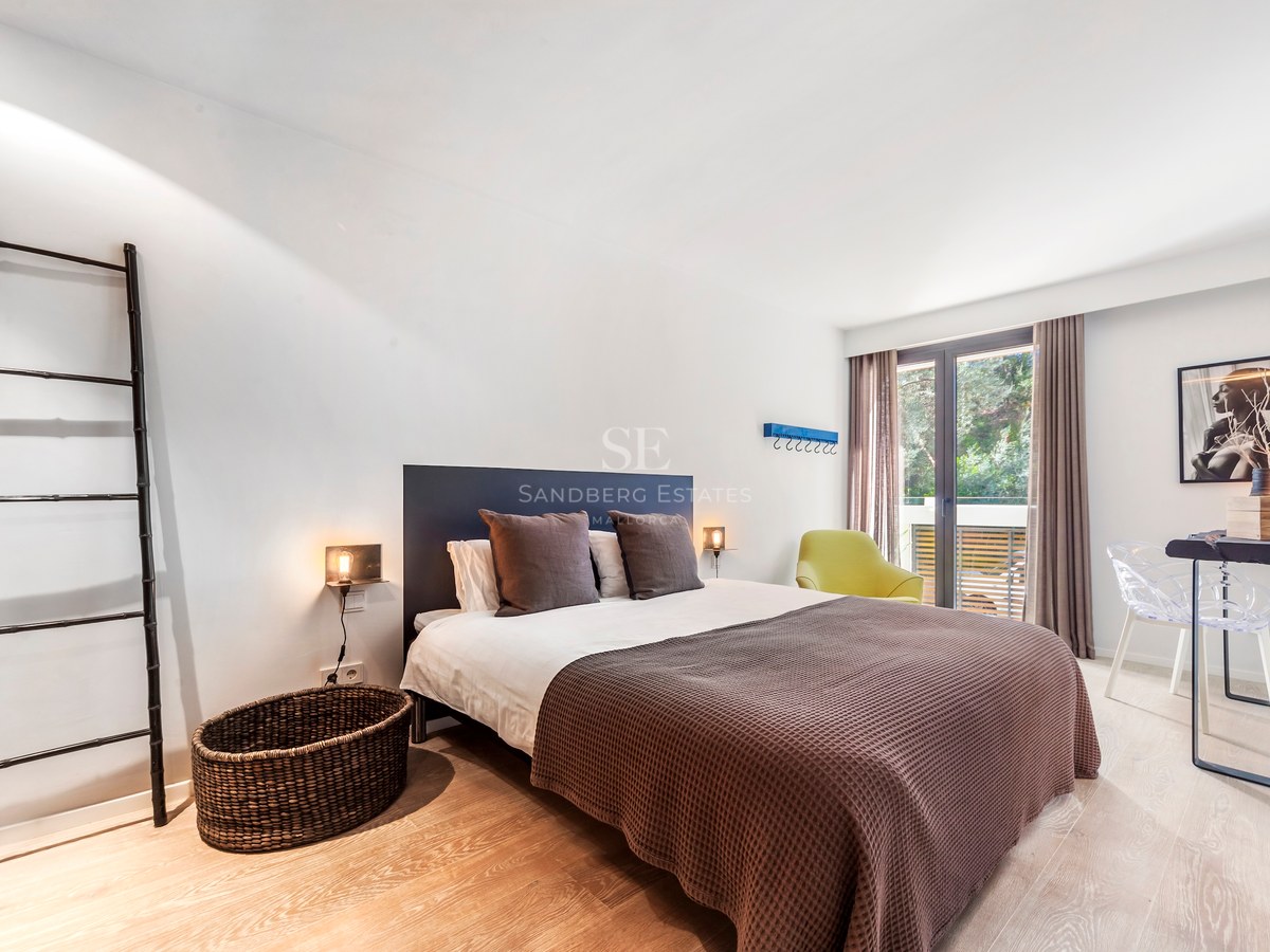 Chambre contemporaine avec lit double, parquet clair et porte vitrée ouvrant sur une terrasse.