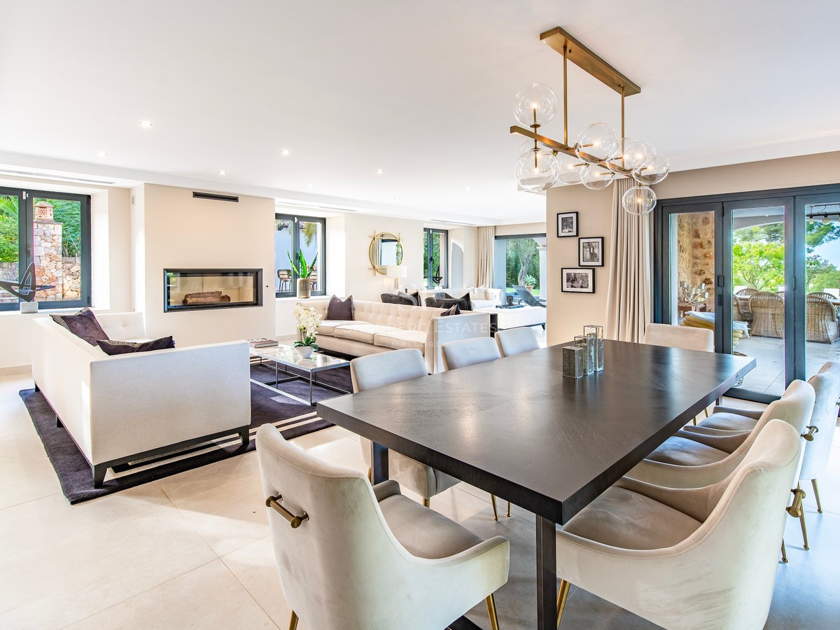 Salón y comedor de diseño contemporáneo con mesa de madera oscura, sofás en crema y chimenea moderna integrada.
