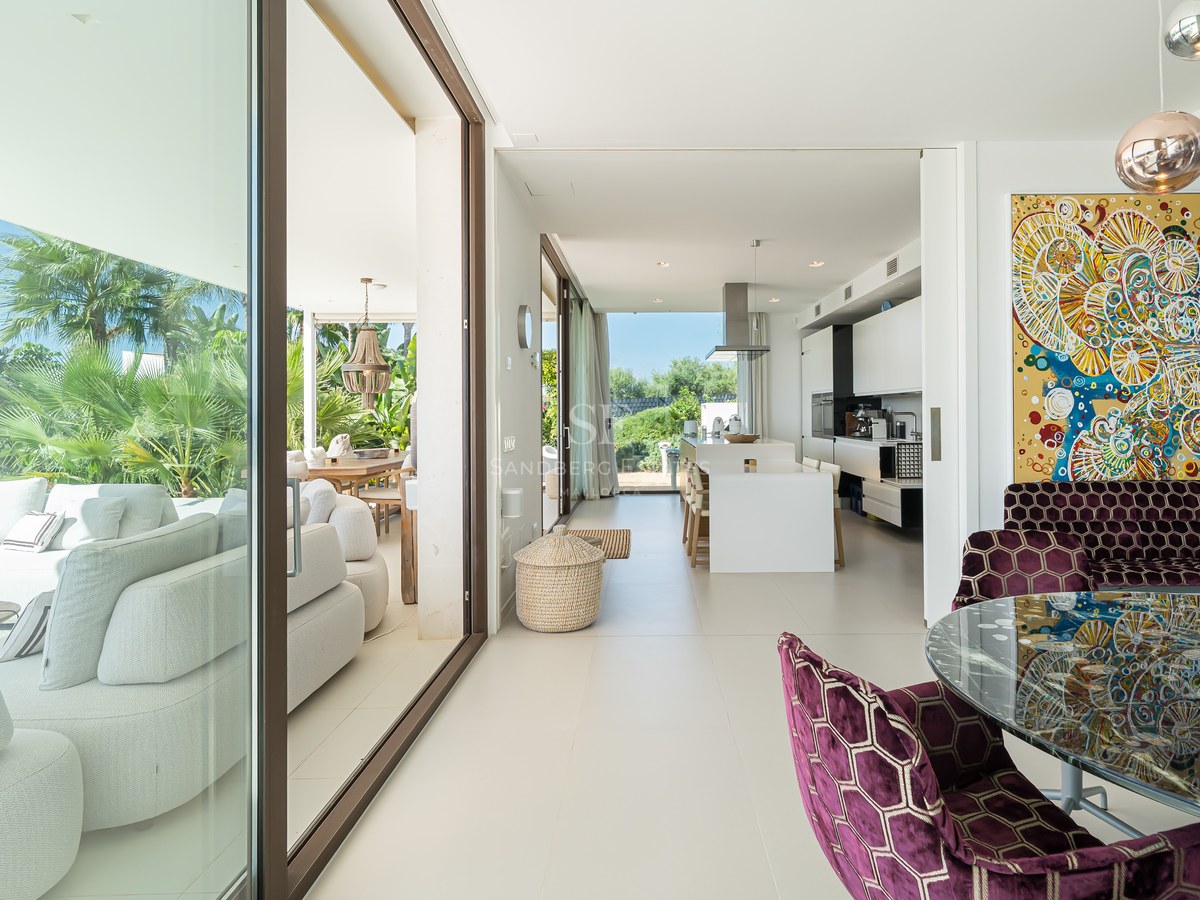 Amplia terraza con piscina infinita y vistas al mar. Diseño moderno, elegante mobiliario y exuberante vegetación.