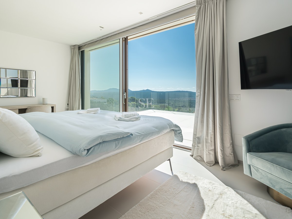 Vista exterior de una villa moderna con piscina infinita, amplias ventanas y arquitectura minimalista. Jardín exuberante y cielo despejado.