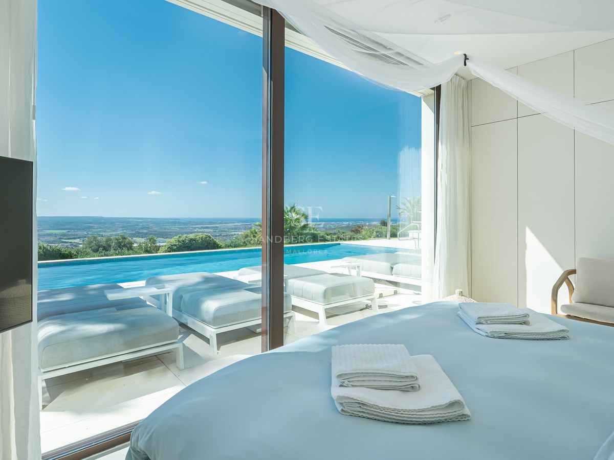 Vista exterior de villa moderna con piscina infinita, amplios ventanales y jardín exuberante. Arquitectura contemporánea y diseño elegante.