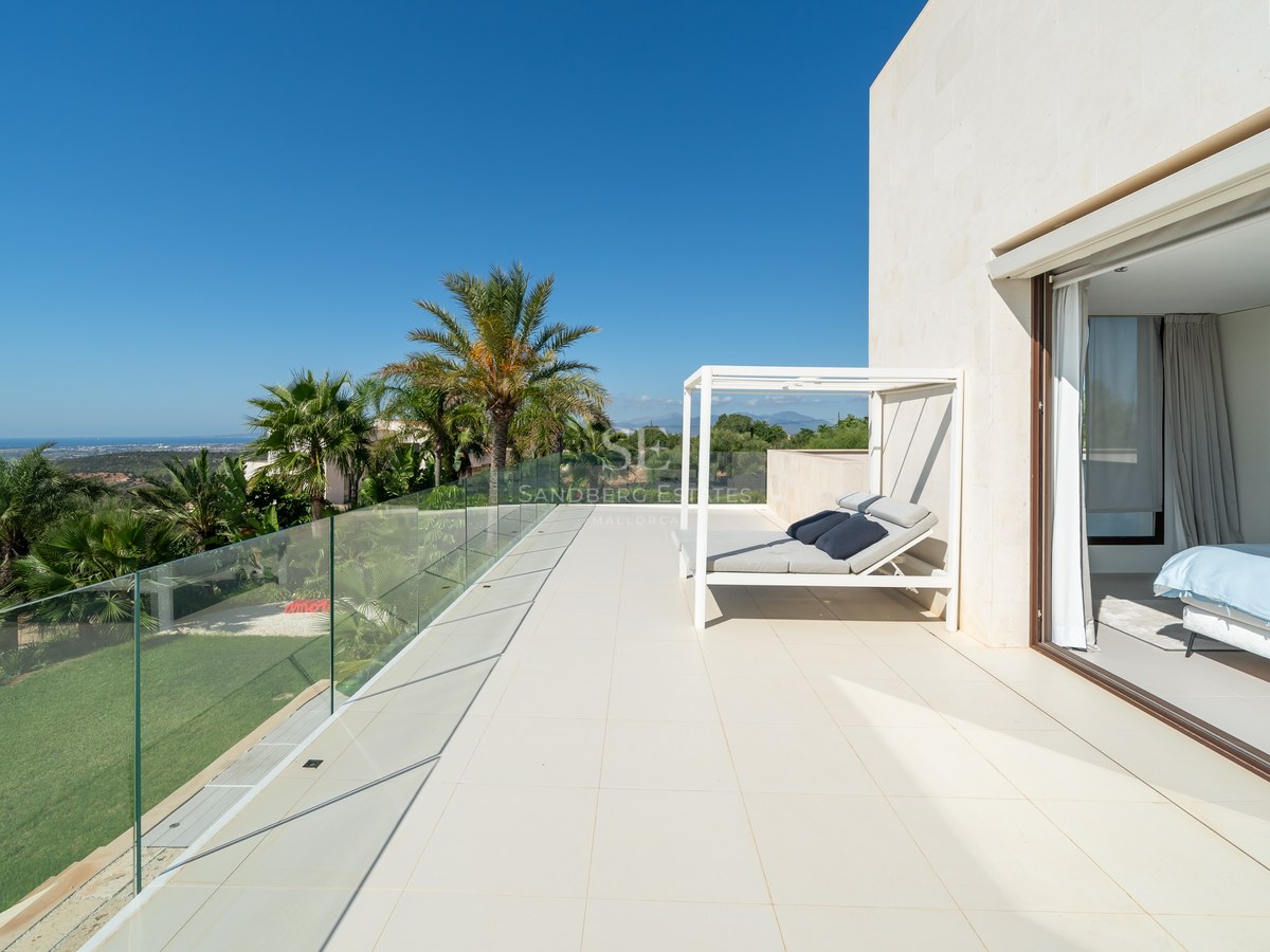 Vista exterior de una villa moderna con piscina, amplias cristaleras y exuberante jardín. Diseño minimalista y acabados de alta calidad.