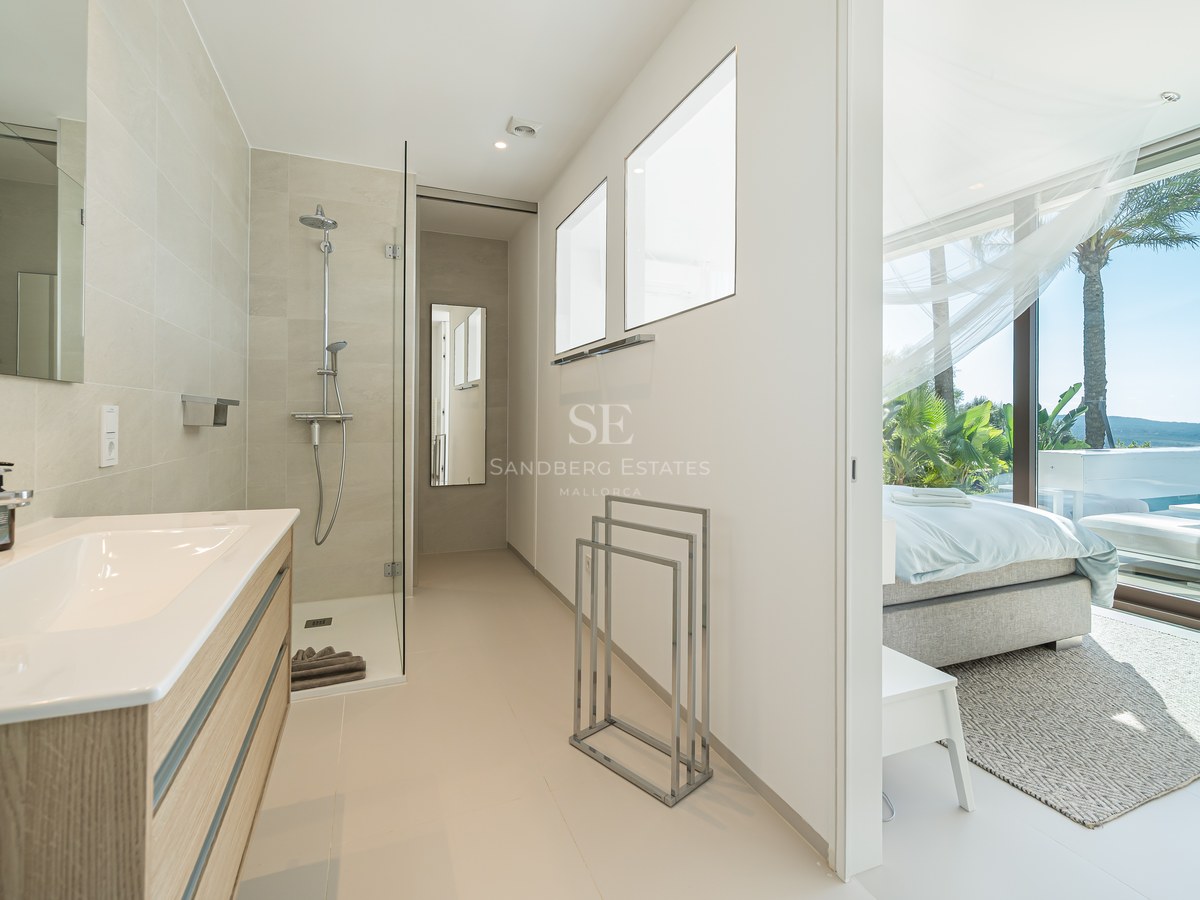 Balcón moderno con barandilla de cristal, vistas impresionantes, muebles de exterior elegantes y suelo de madera. Diseño minimalista y luminoso.